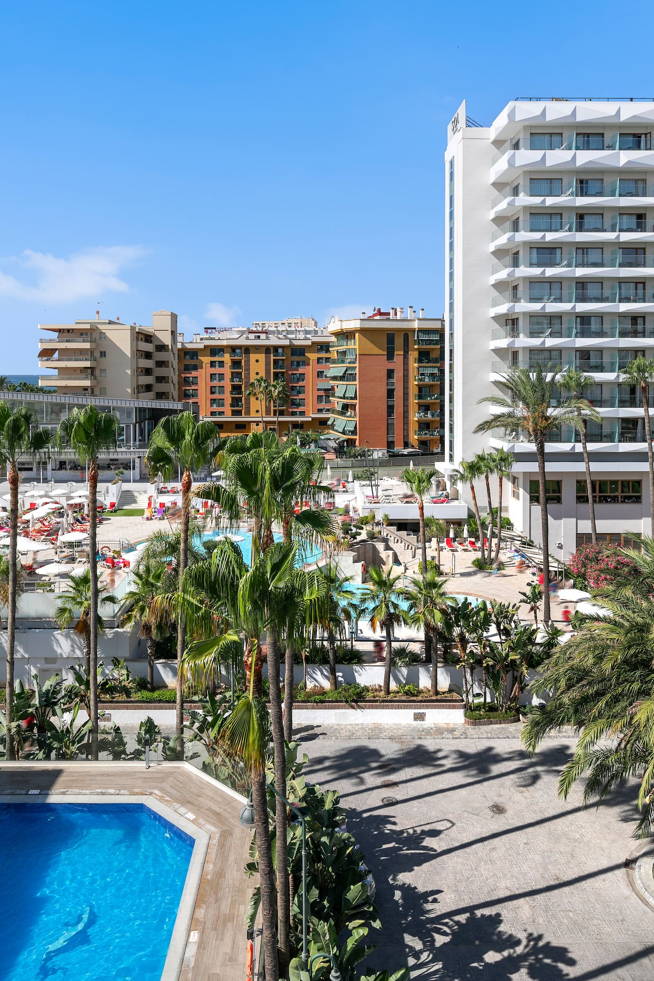 a pool and palm trees in front of buildings