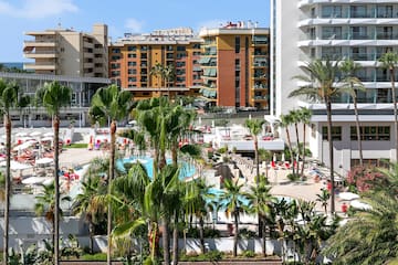 a pool and palm trees in front of buildings