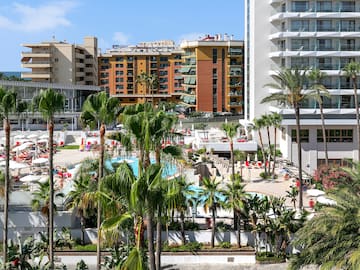 a pool and palm trees in front of buildings