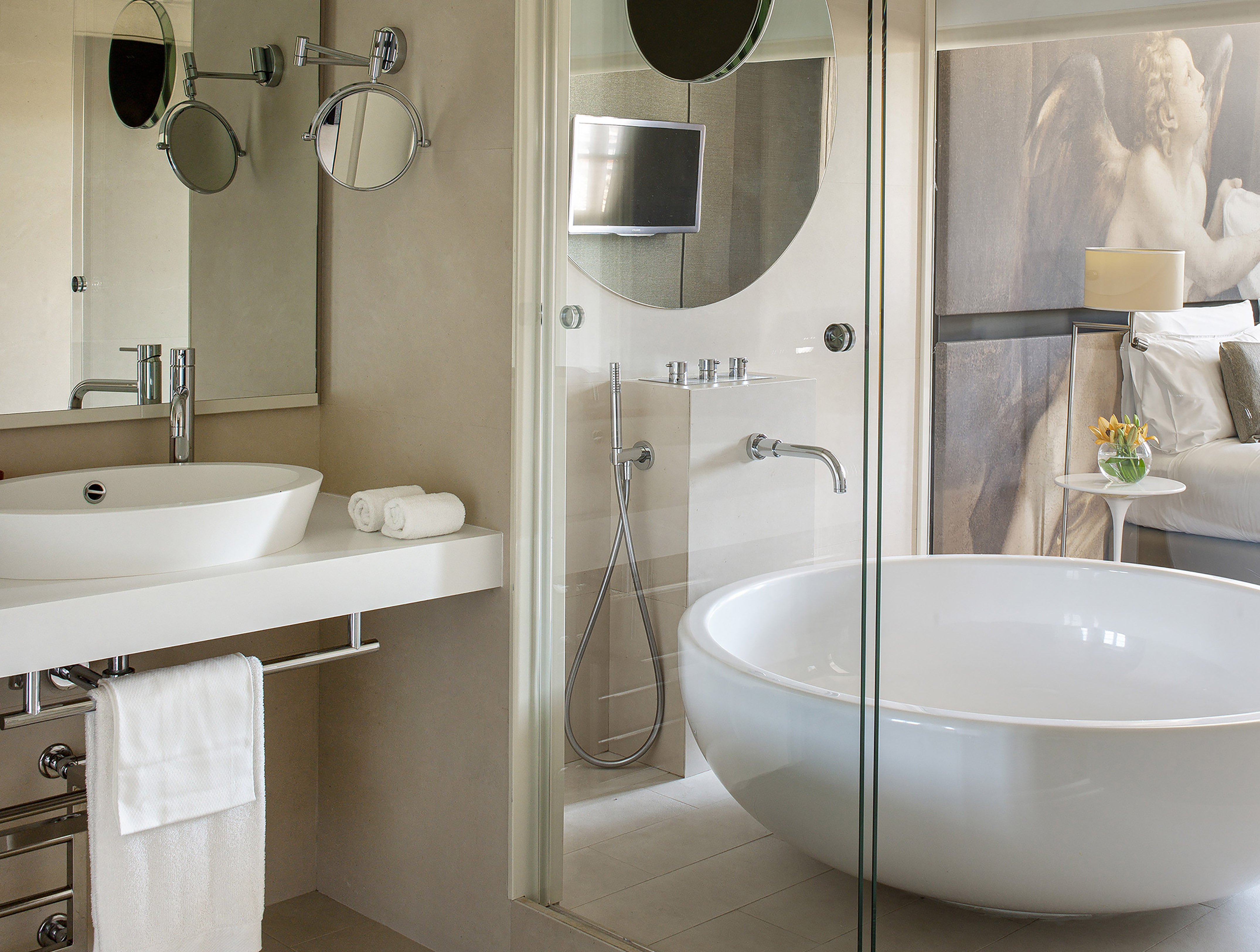 Luxury modern bathroom suite with freestanding tub, glass shower, and sink.