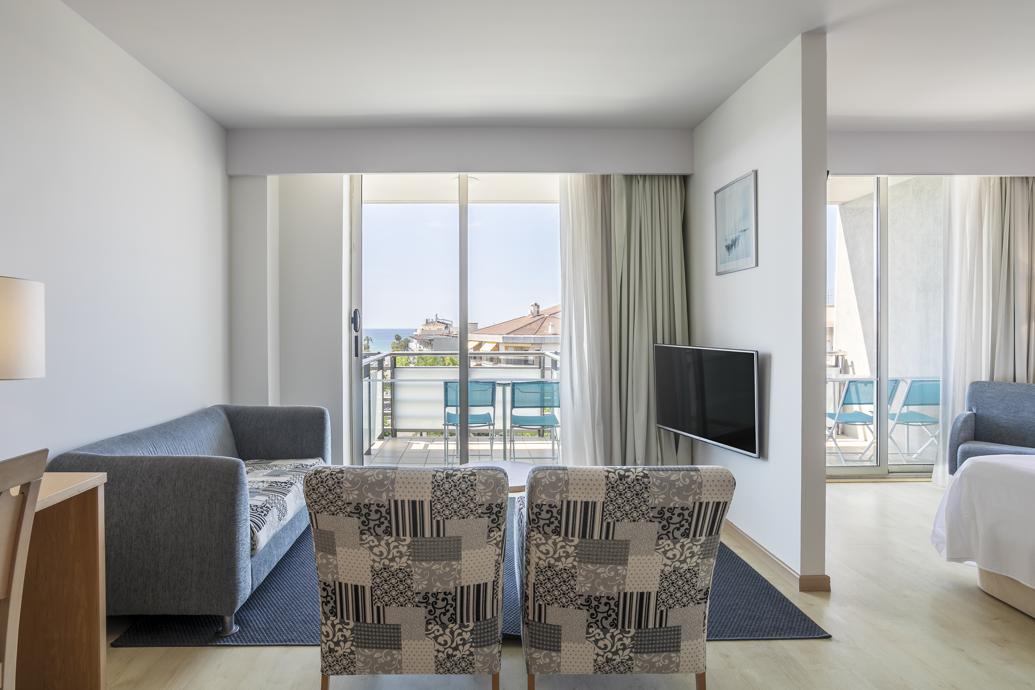 Modern hotel suite living area with ocean view balcony and sofa.