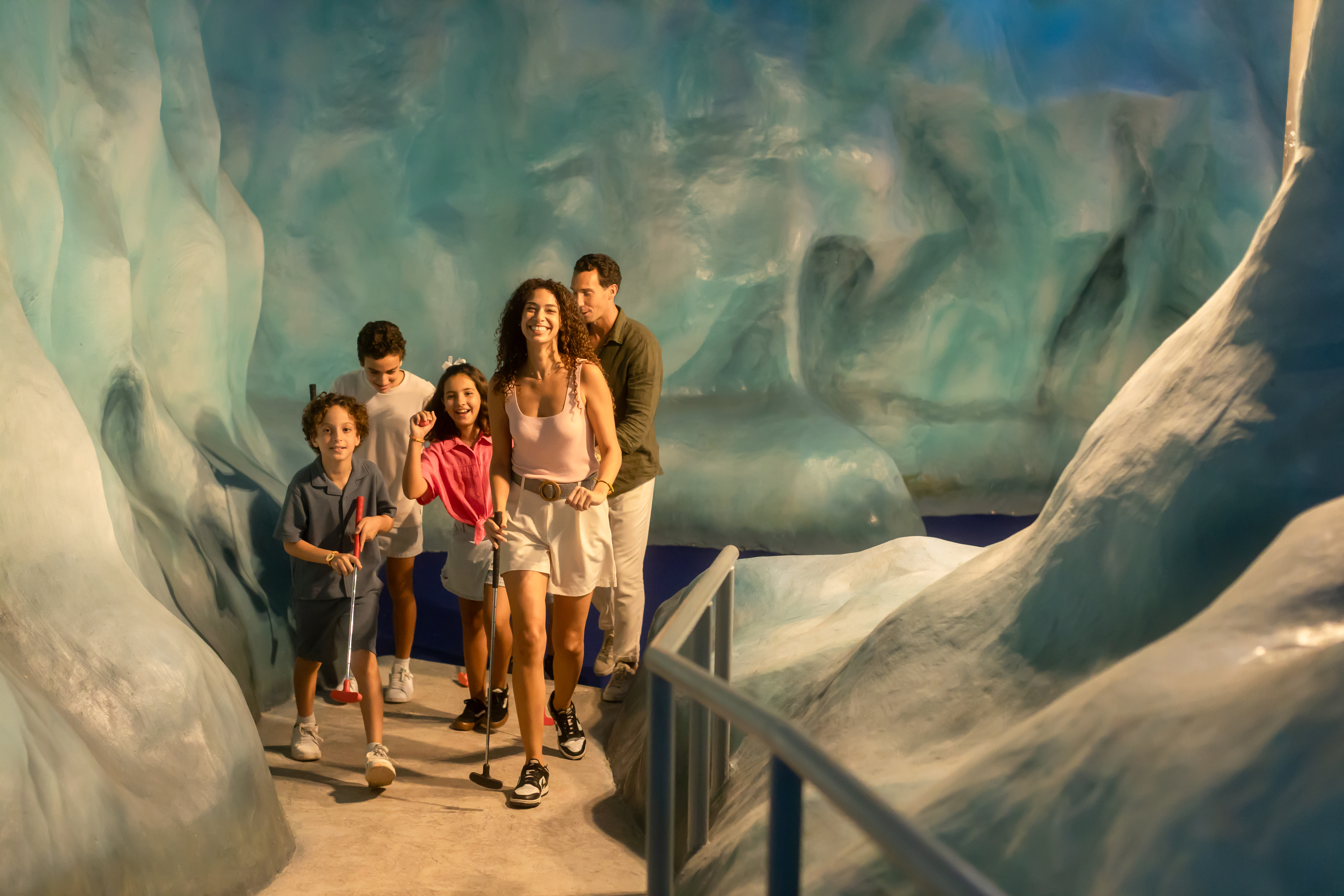 Family playing indoor mini golf in an ice cave themed environment.