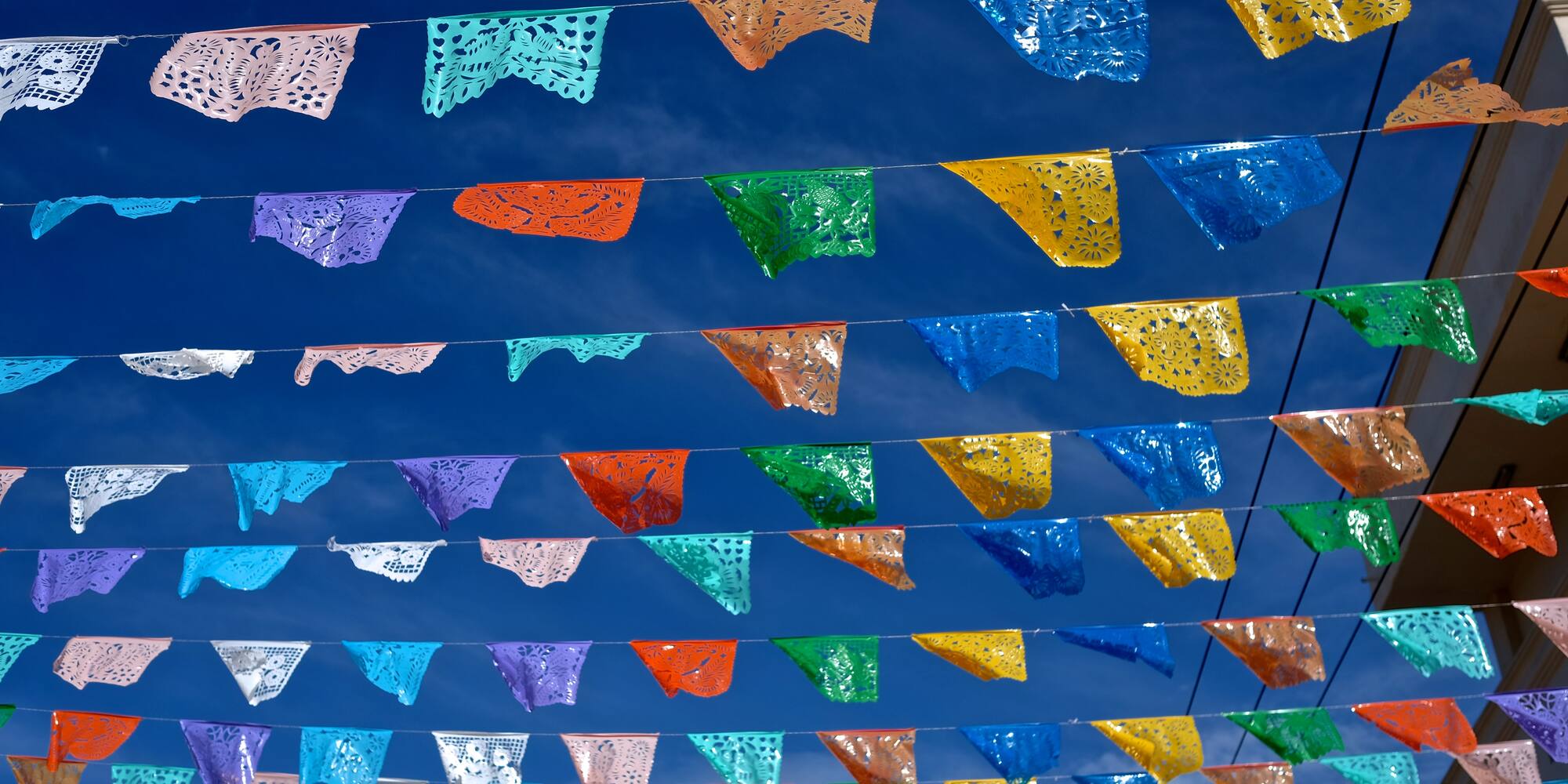 Banderines de papel picado coloridos, fiesta mexicana bajo cielo azul.