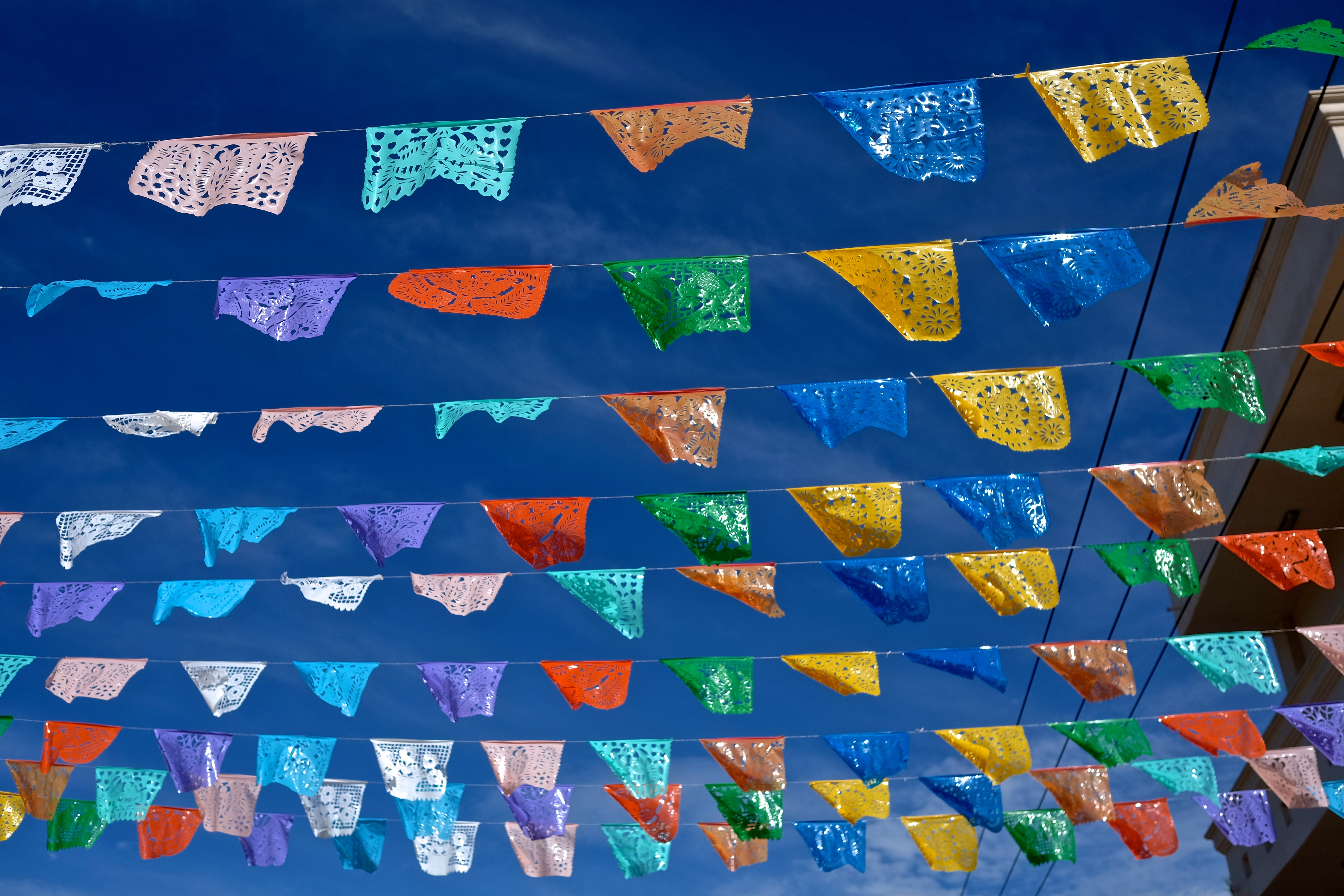 Guirnaldas de papel picado mexicano coloridas contra cielo azul.