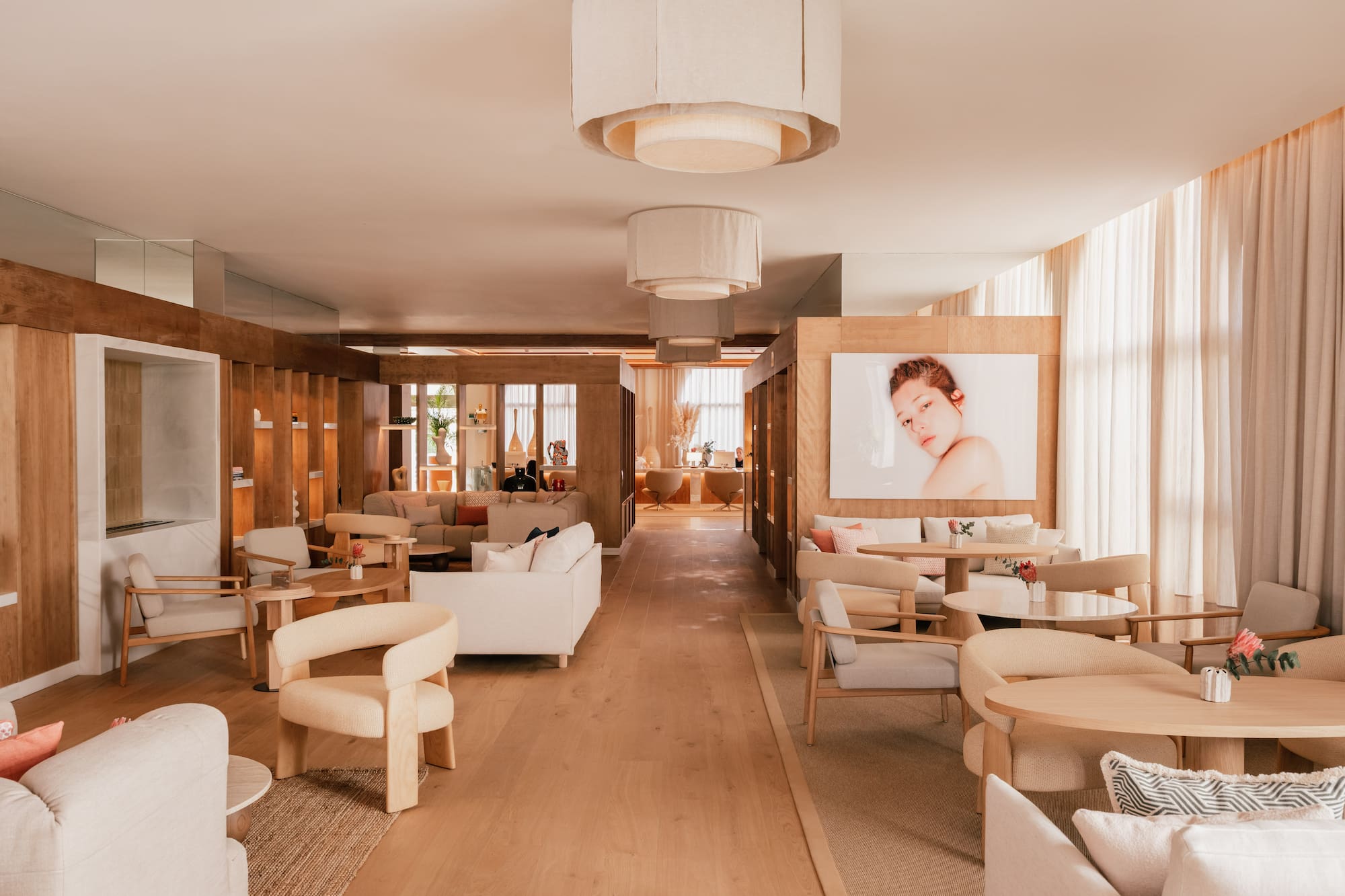 Modern lounge with neutral tones, light wood, inviting seating, and ceiling lamps.