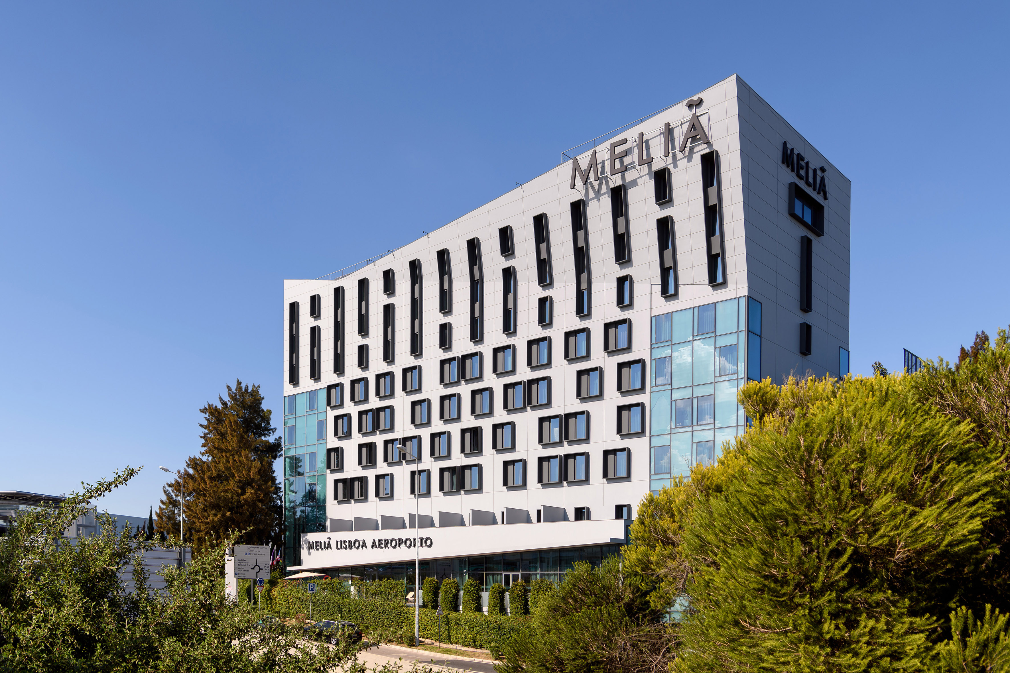 Modern Meliá Lisboa Aeroporto hotel facade with windows under blue sky.