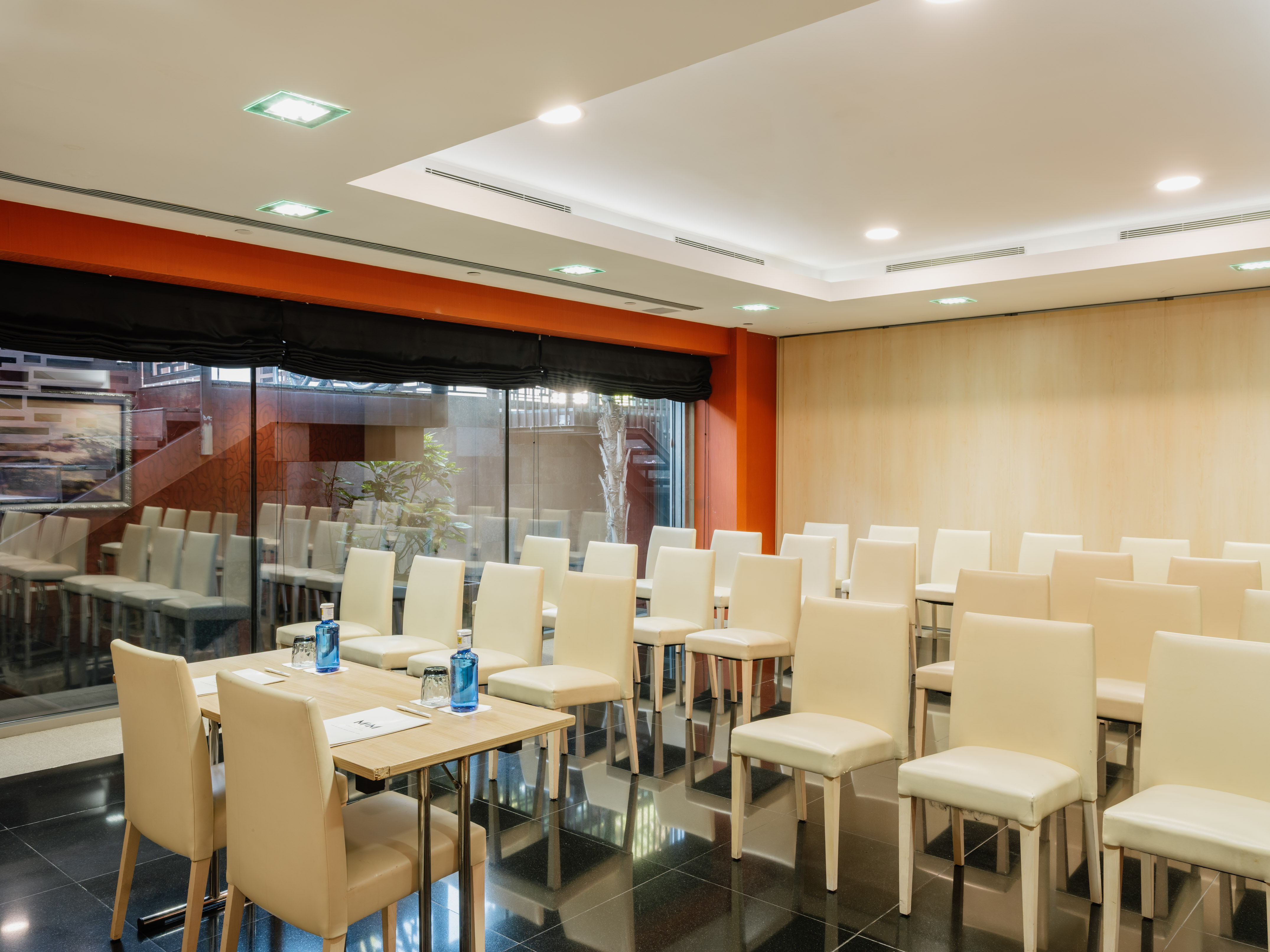 Empty modern meeting room with cream chairs, wooden table, and large windows.