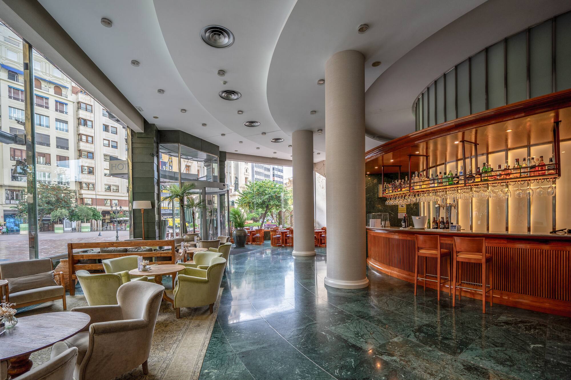 Elegant hotel lounge bar, plush seating, green marble floor, city views.