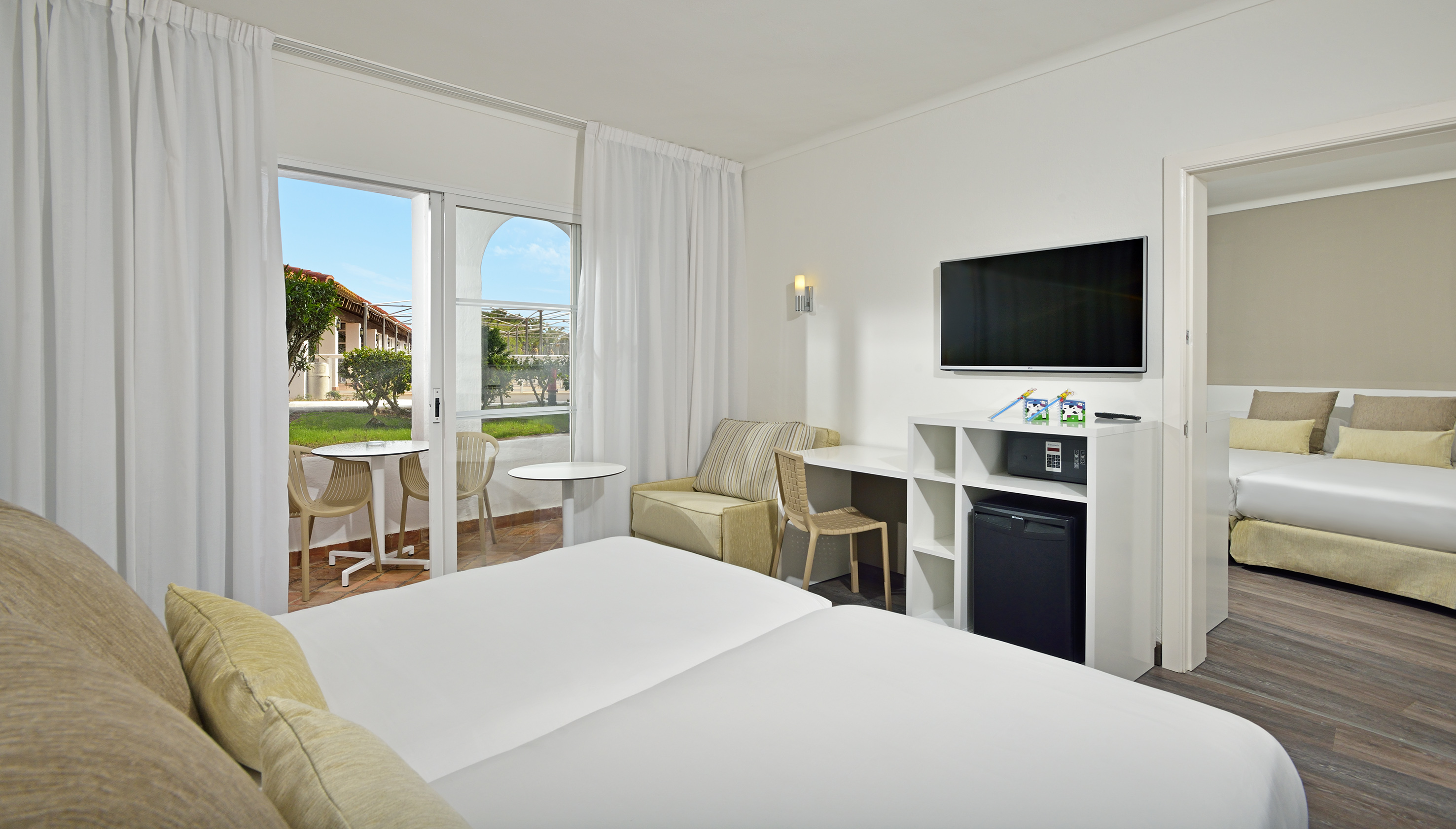 Hotel family room with twin beds, private patio, and connected bedroom.