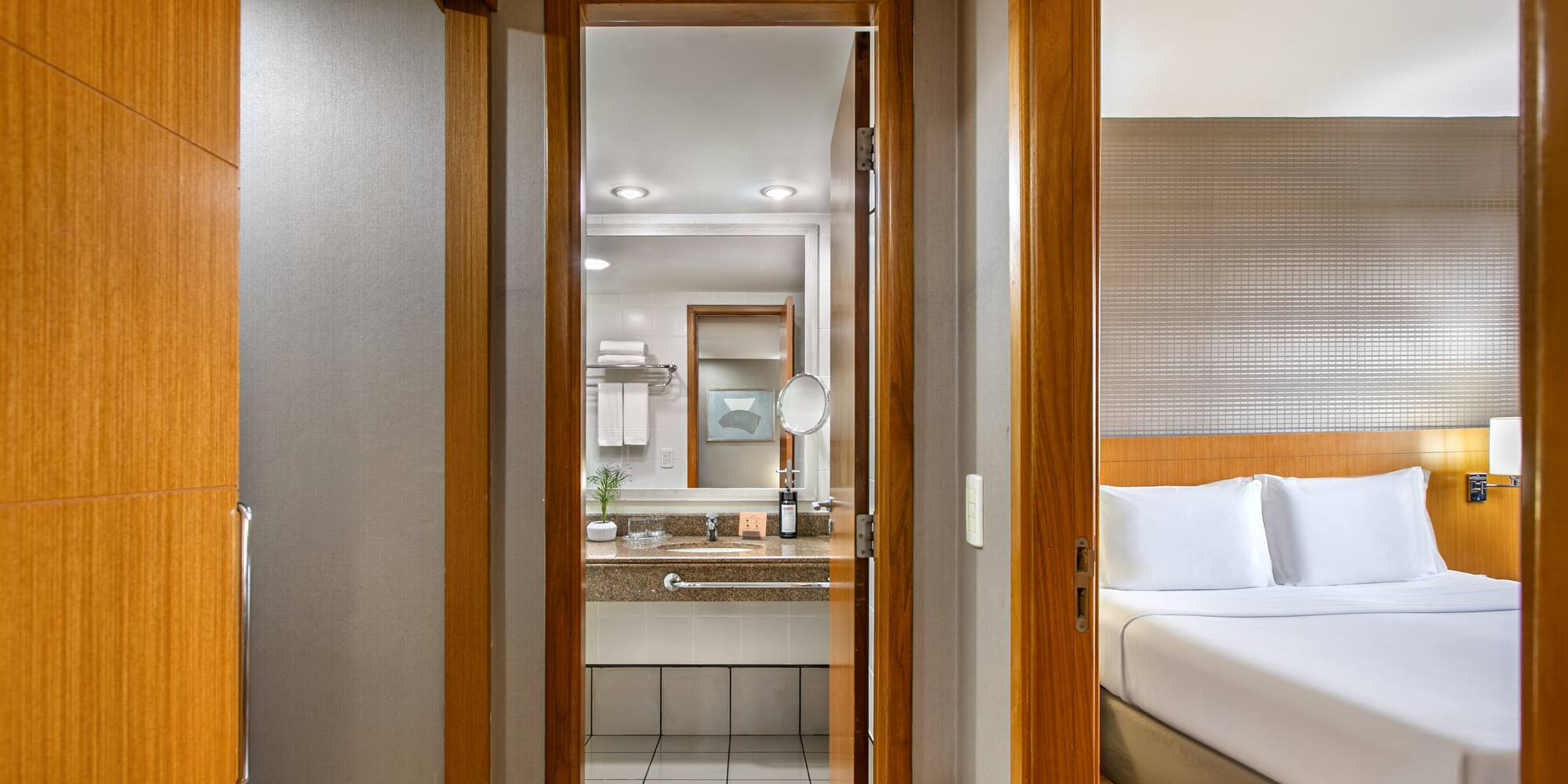 Modern hotel room with open doors showing bedroom and bathroom.