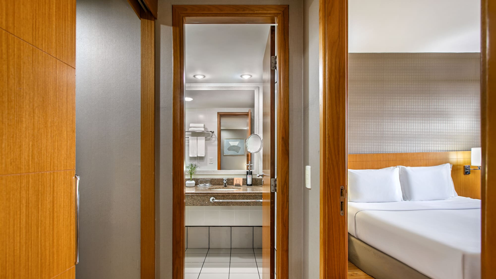Modern hotel room with open doors showing bedroom and bathroom.