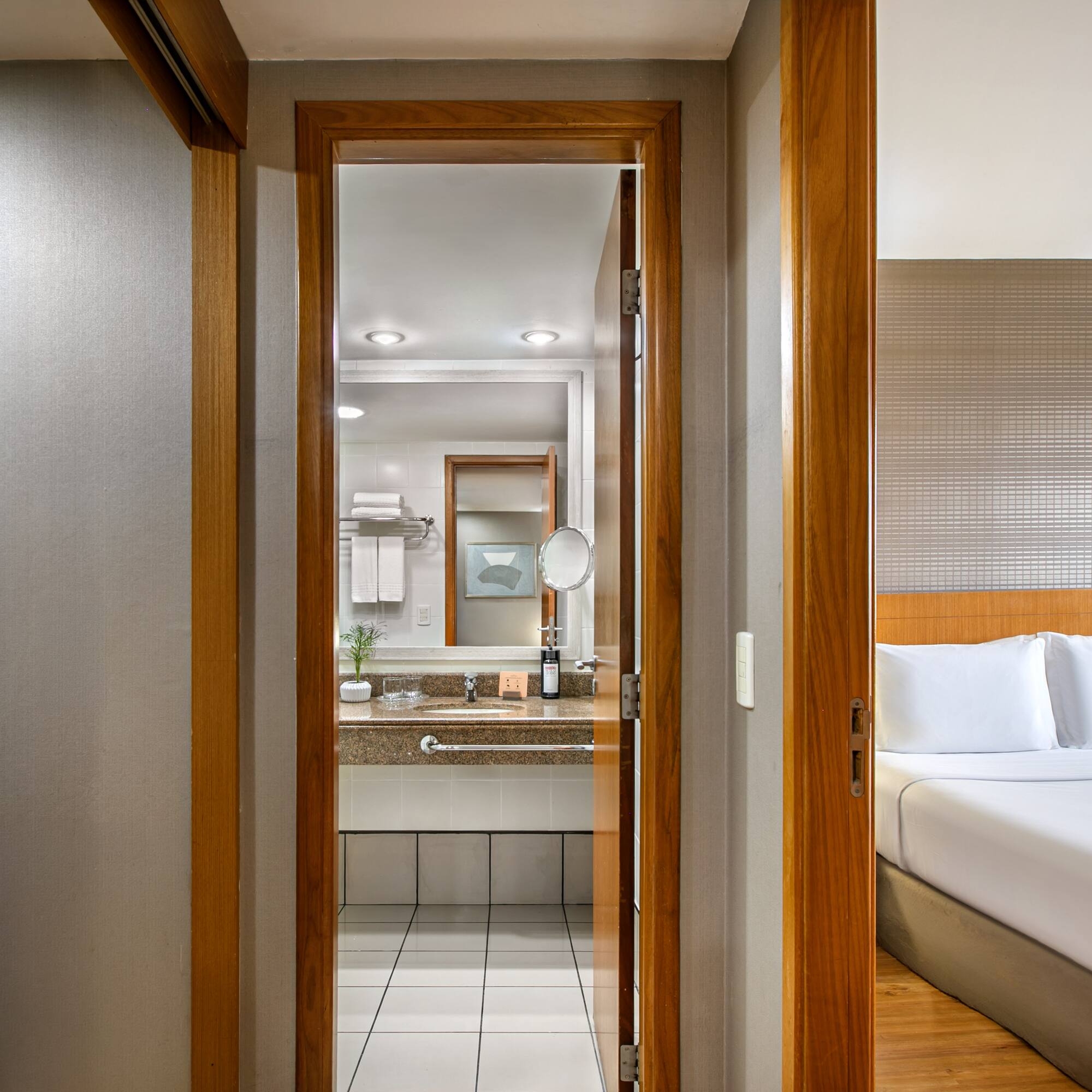 Modern hotel room with open doors showing bedroom and bathroom.