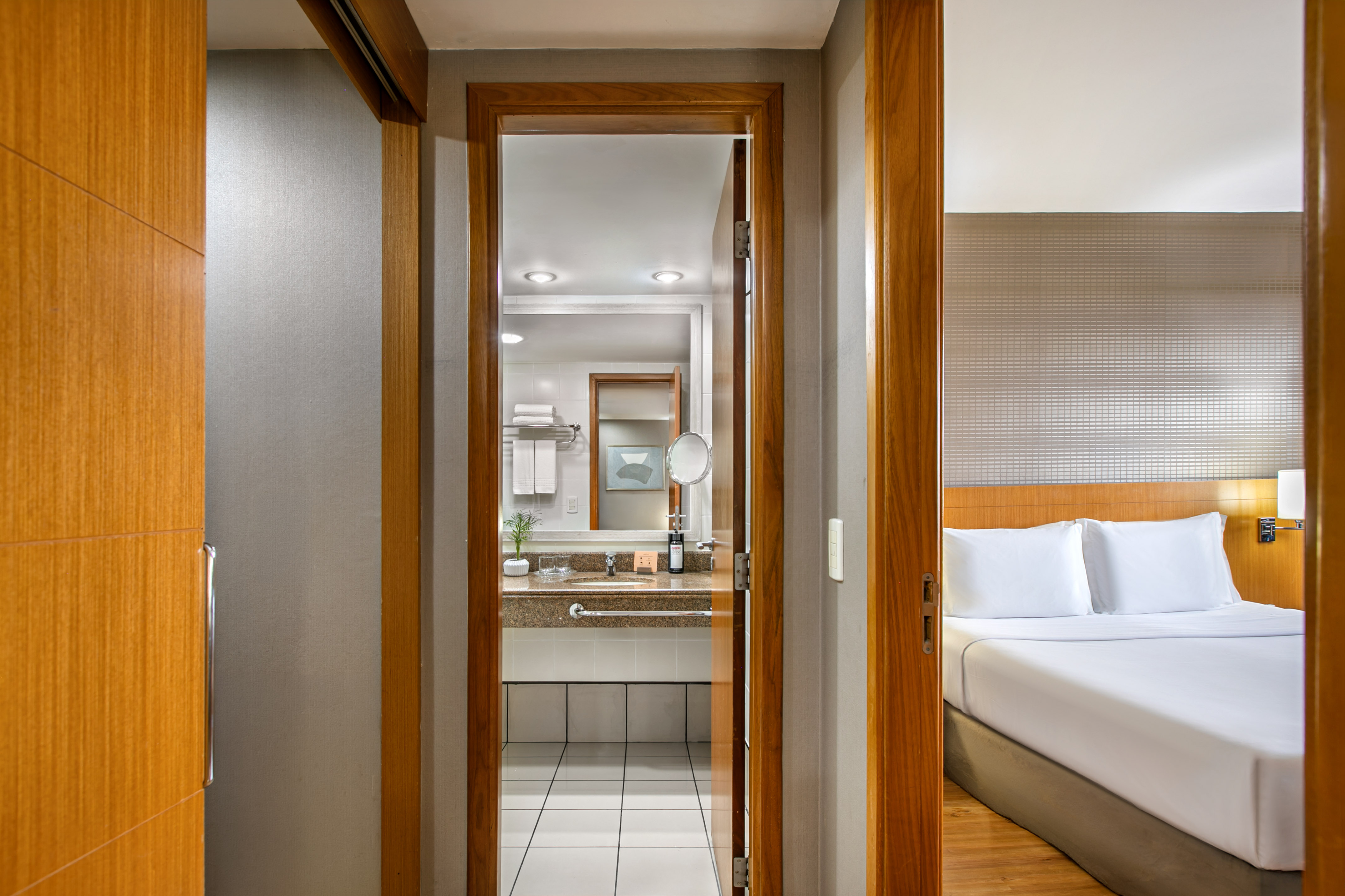 Modern hotel room with open doors showing bedroom and bathroom.