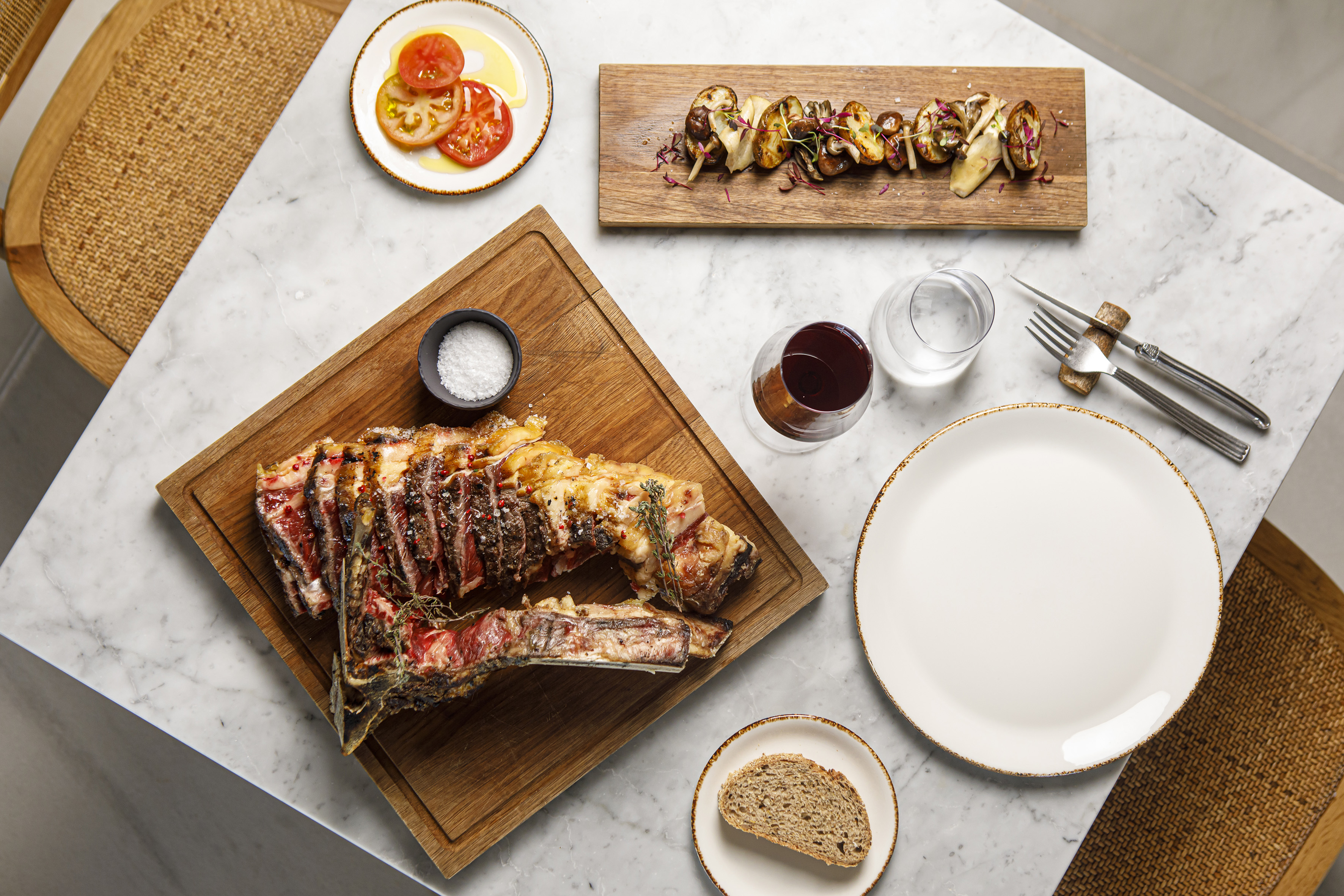 Grilled ribeye steak, roasted mushrooms, fresh tomatoes, red wine, gourmet dining.