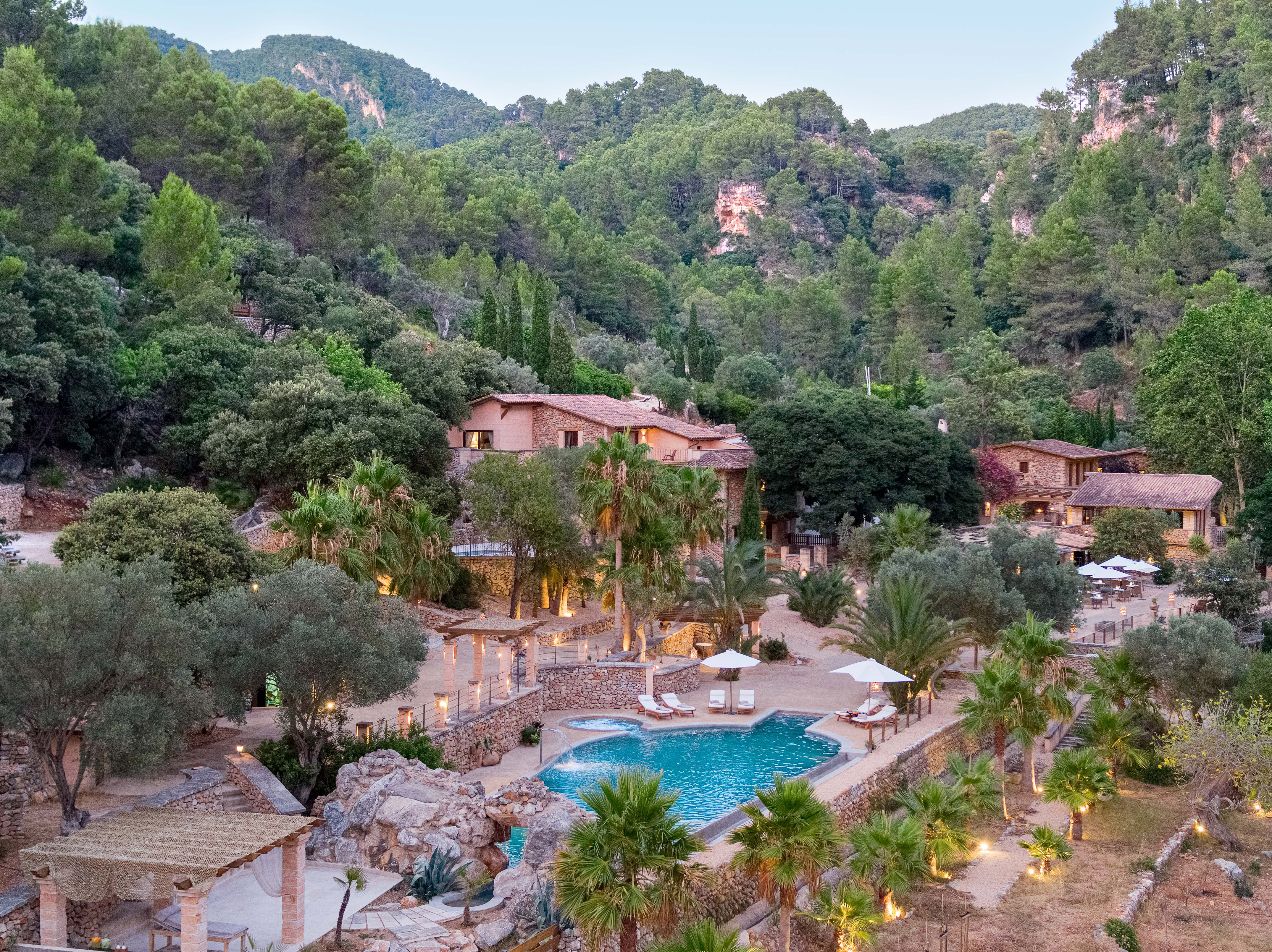 Luxury Mediterranean resort with pool, villas, and lush mountain landscape.