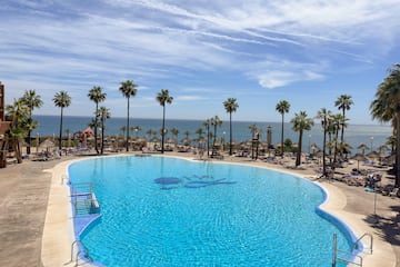 a pool with palm trees and a beach and a body of water
