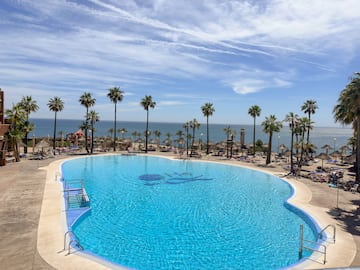 a pool with palm trees and a beach and a body of water