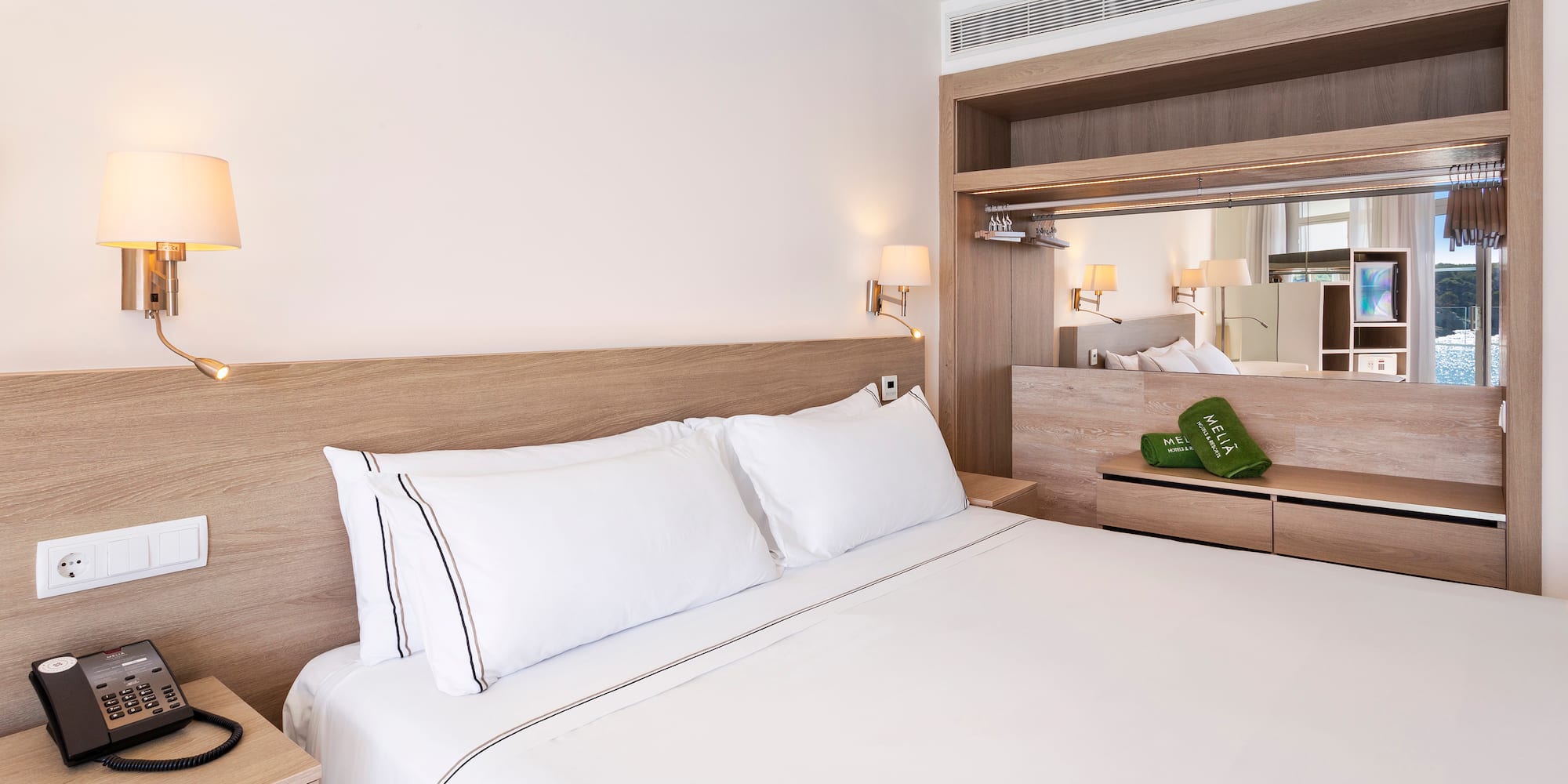 a bed with white sheets and a wood headboard