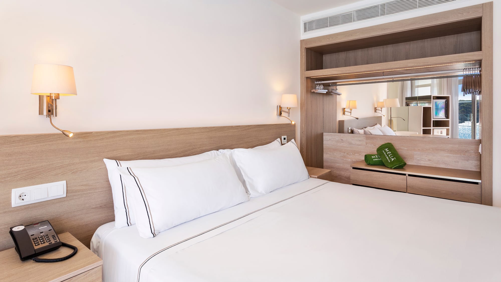 a bed with white sheets and a wood headboard