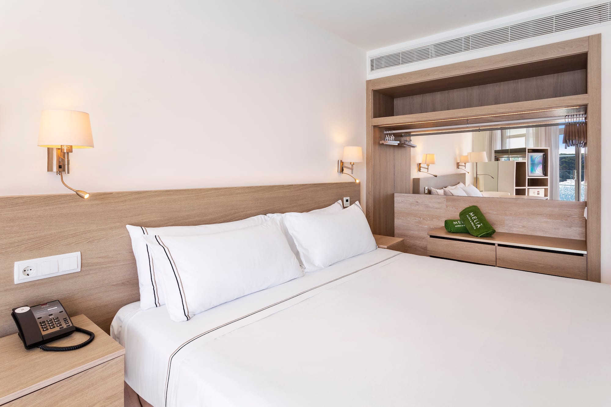 a bed with white sheets and a wood headboard