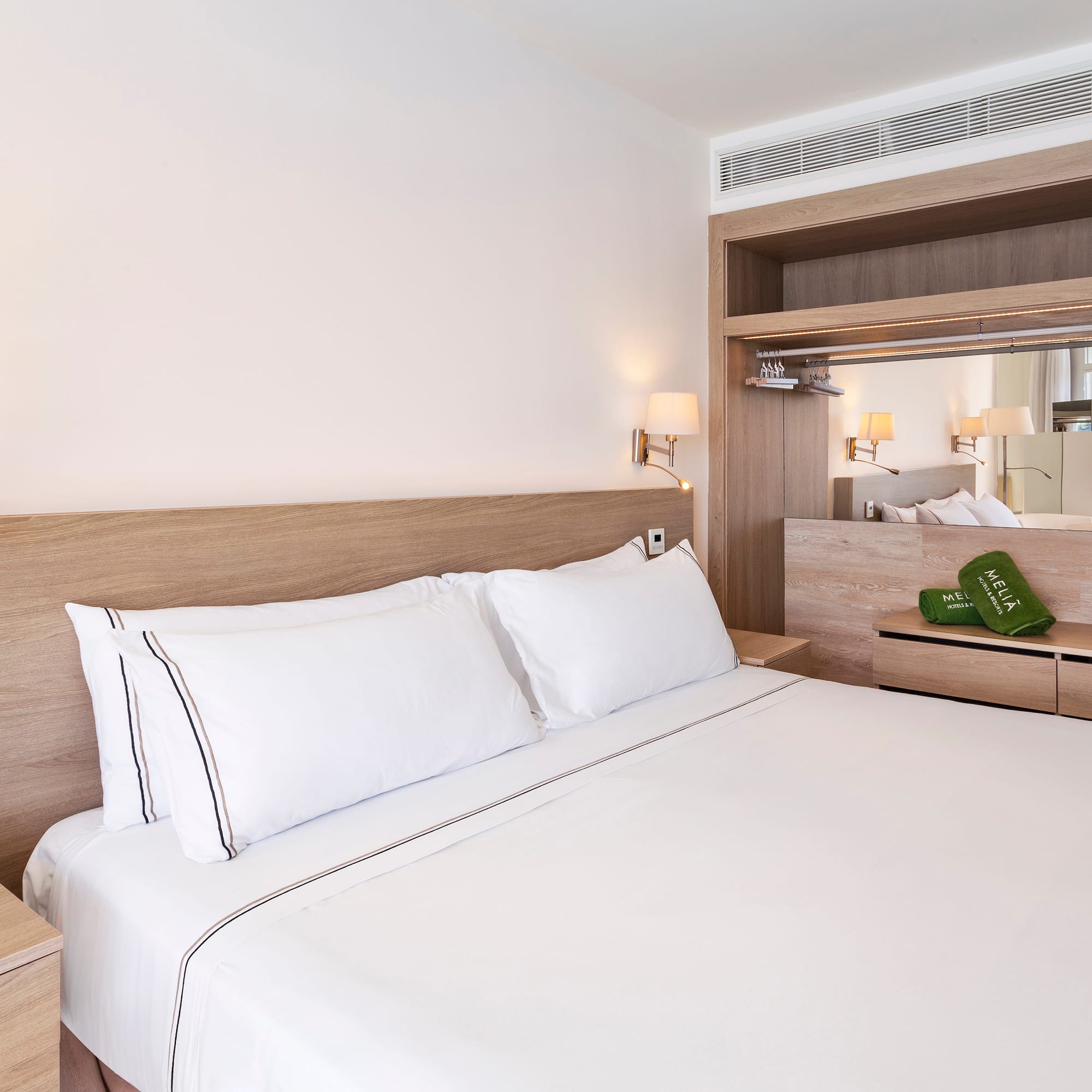 a bed with white sheets and a wood headboard