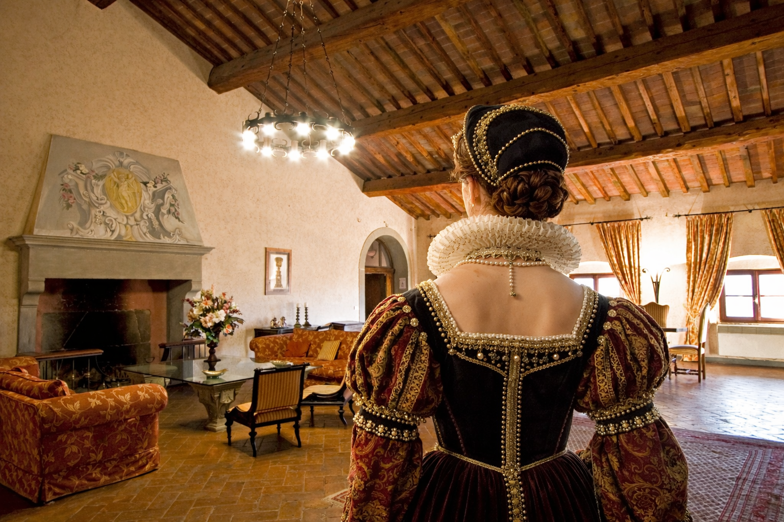 Woman in elaborate Renaissance costume, viewing a grand historic villa interior.