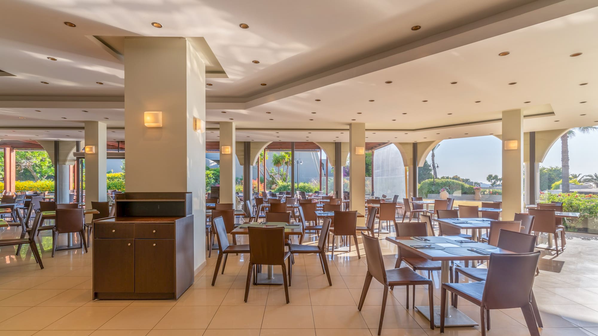 Modern resort restaurant with tables, chairs, and bright garden views.