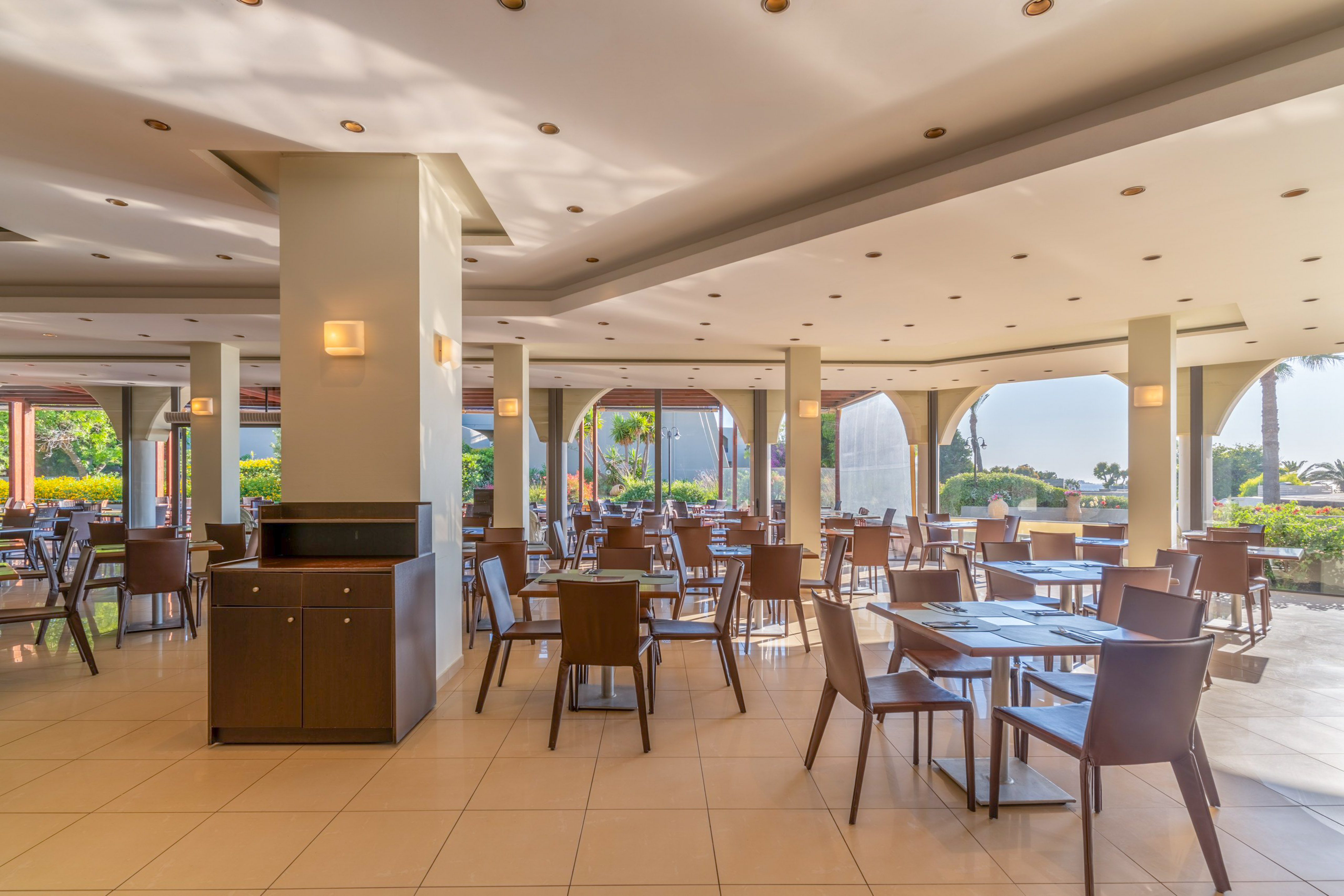 Modern resort restaurant with tables, chairs, and bright garden views.