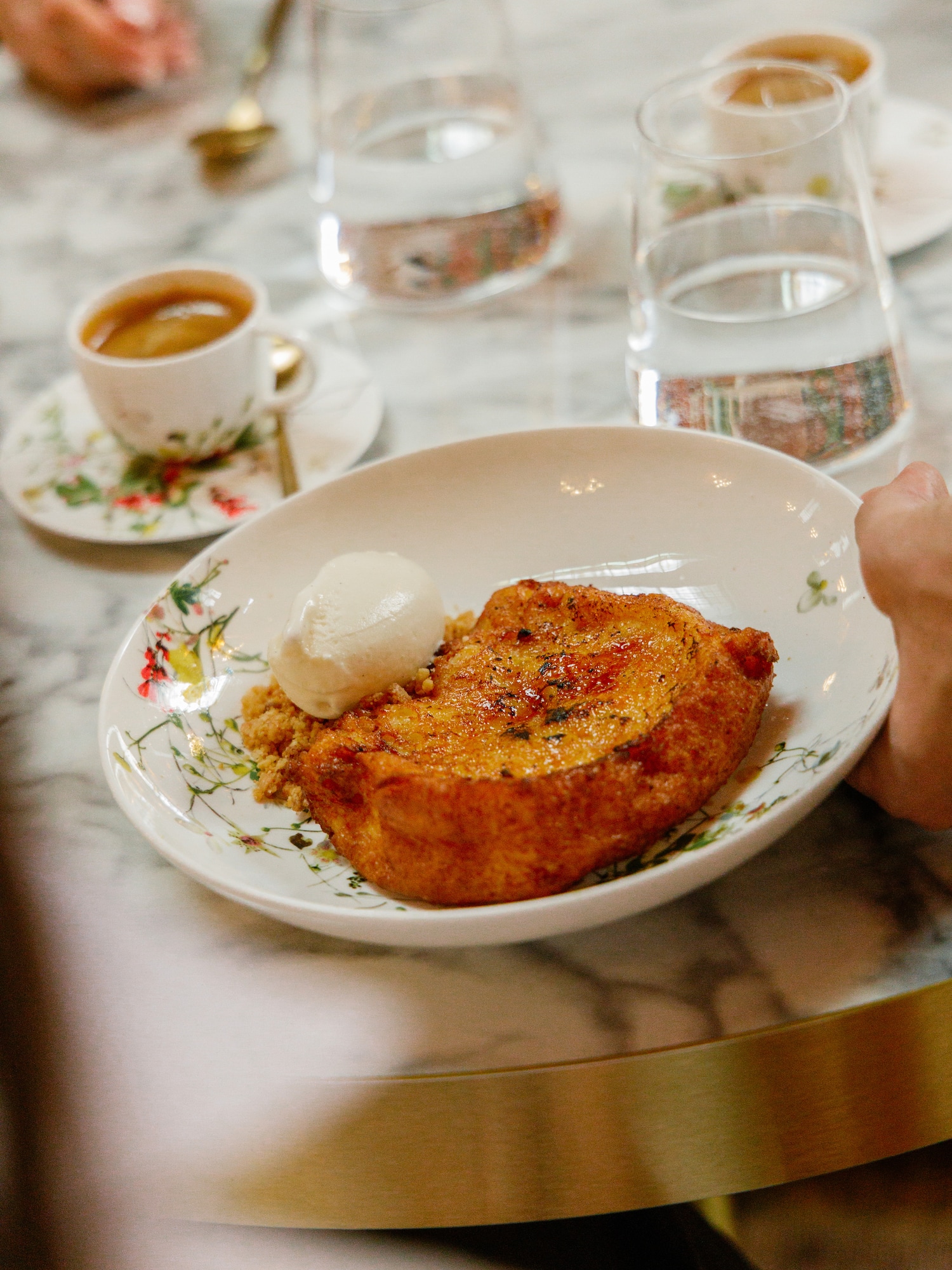 Decadent French toast with ice cream, espresso, and water on an elegant marble table.