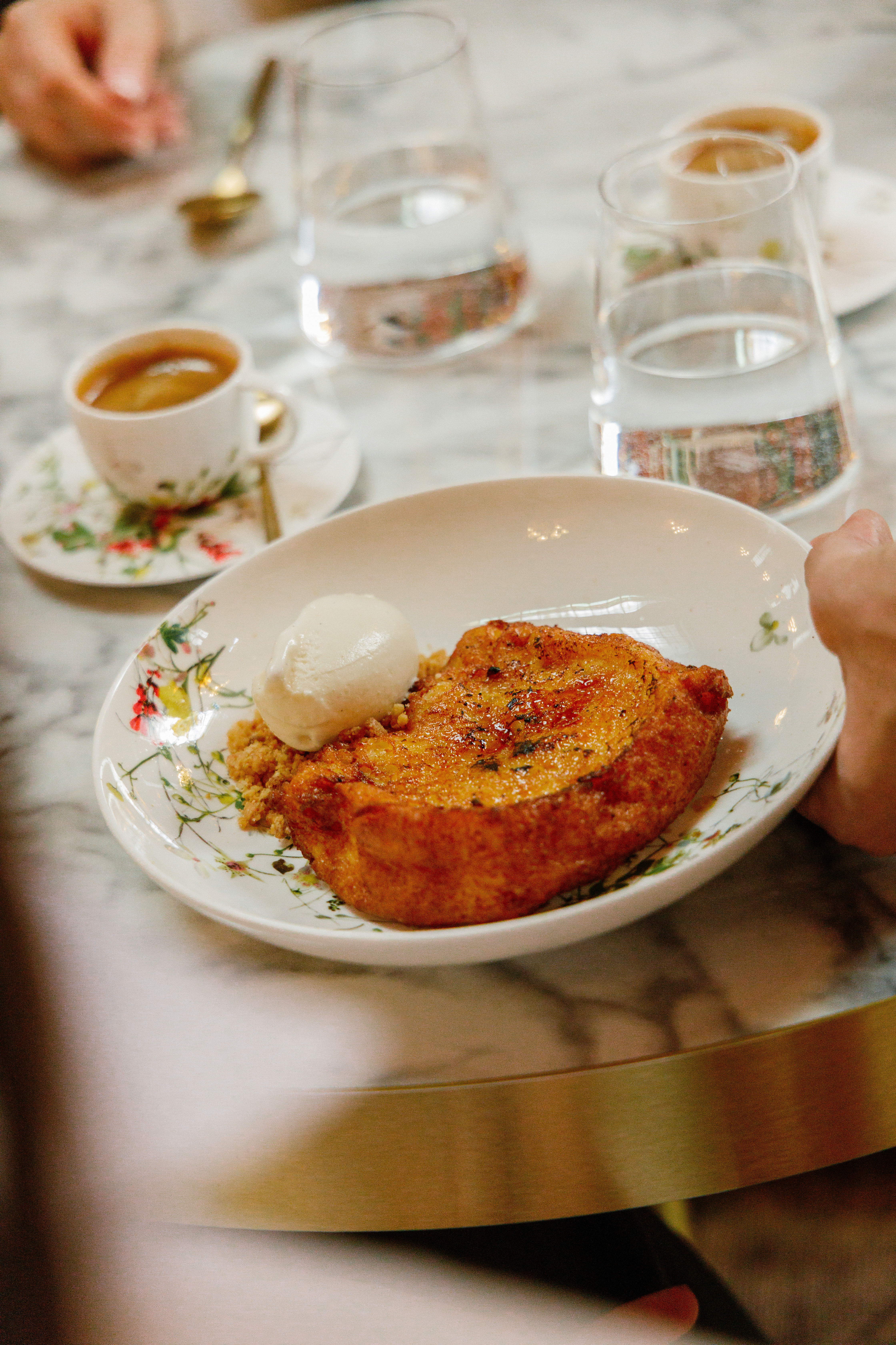 Decadent French toast with ice cream, espresso, and water on an elegant marble table.