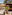 Beachfront bar and restaurant with thatch umbrellas, wooden deck, and palm trees.