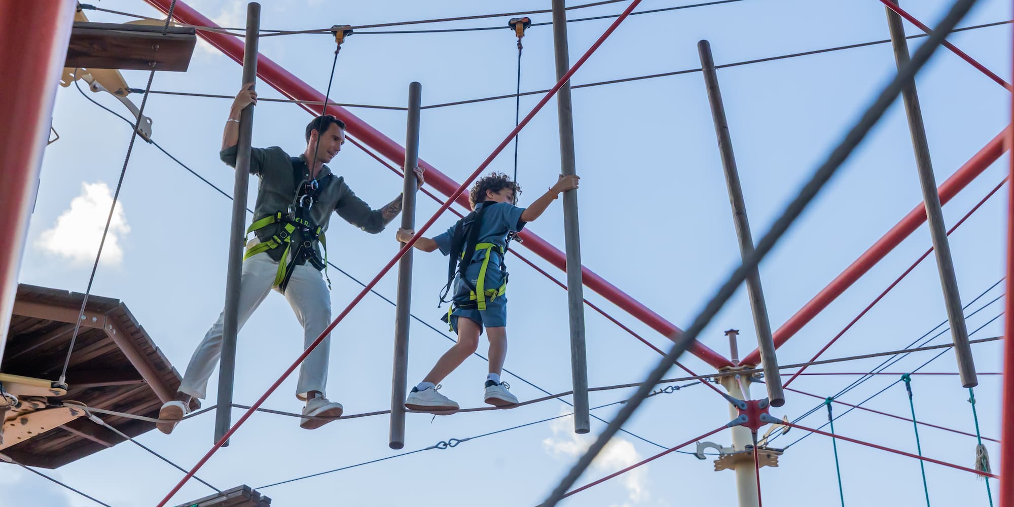 a man and boy walking on a rope bridge