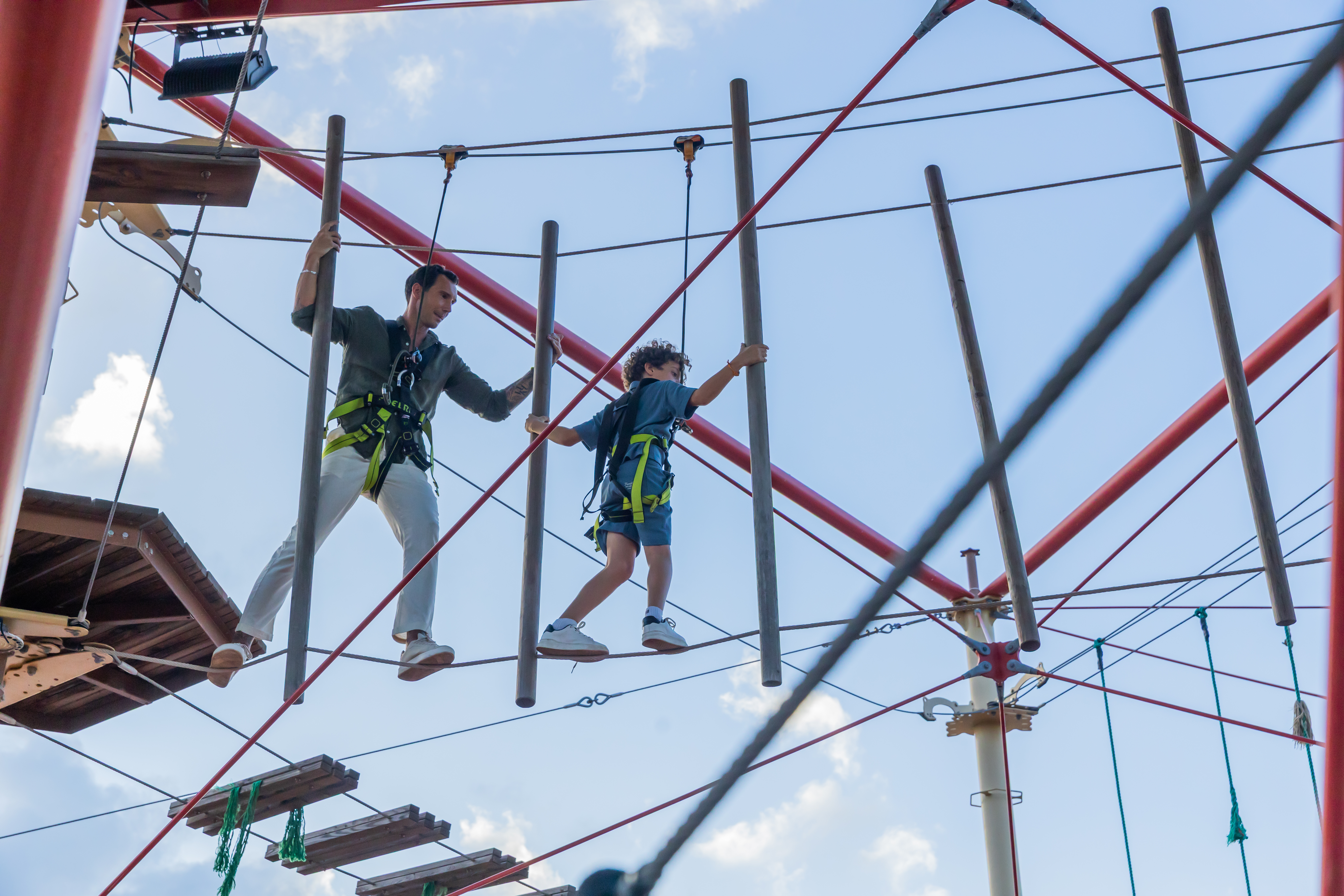 a man and boy walking on a rope bridge