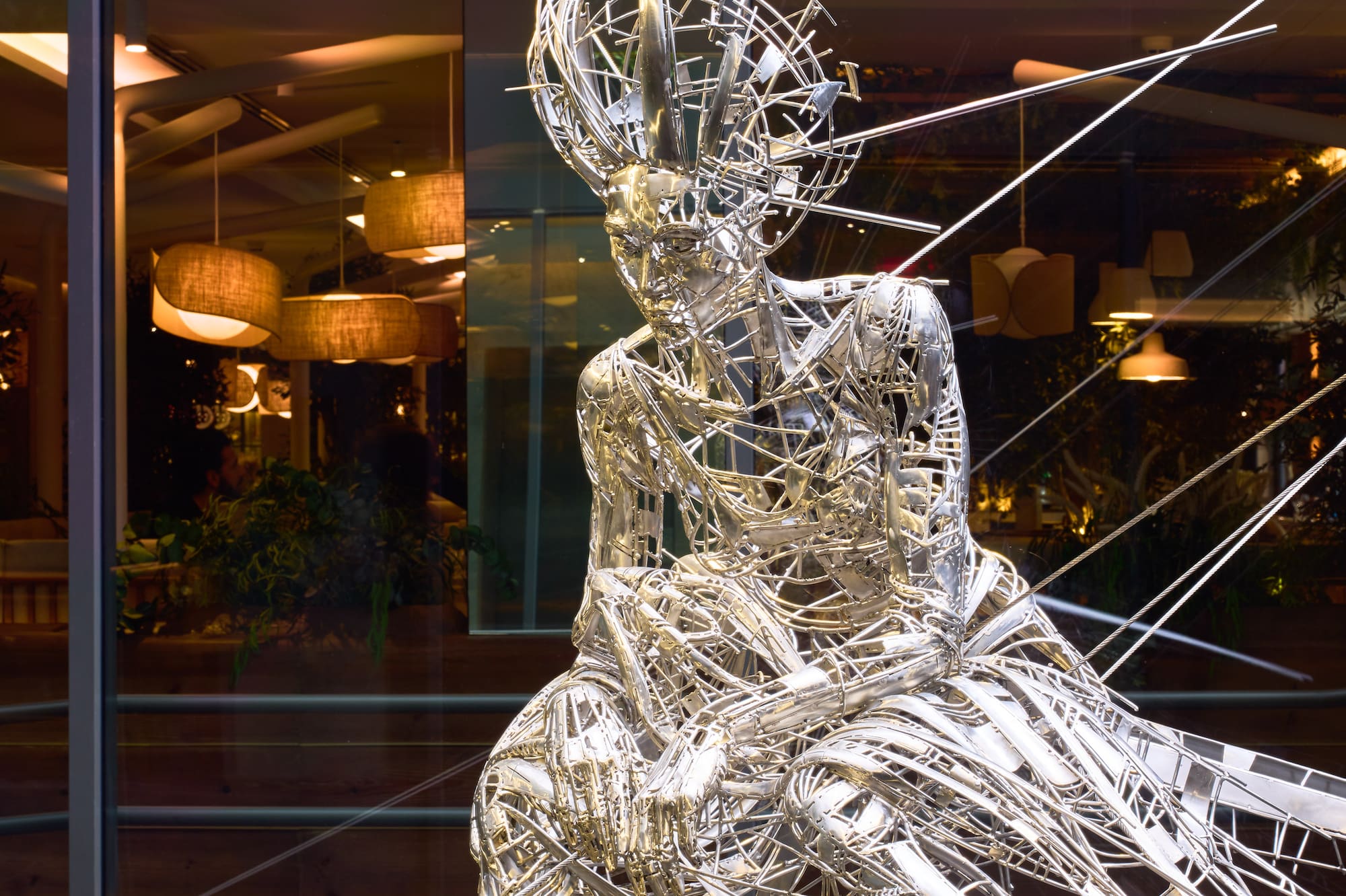 Abstract metal wire sculpture of figure with spiked head, window display.