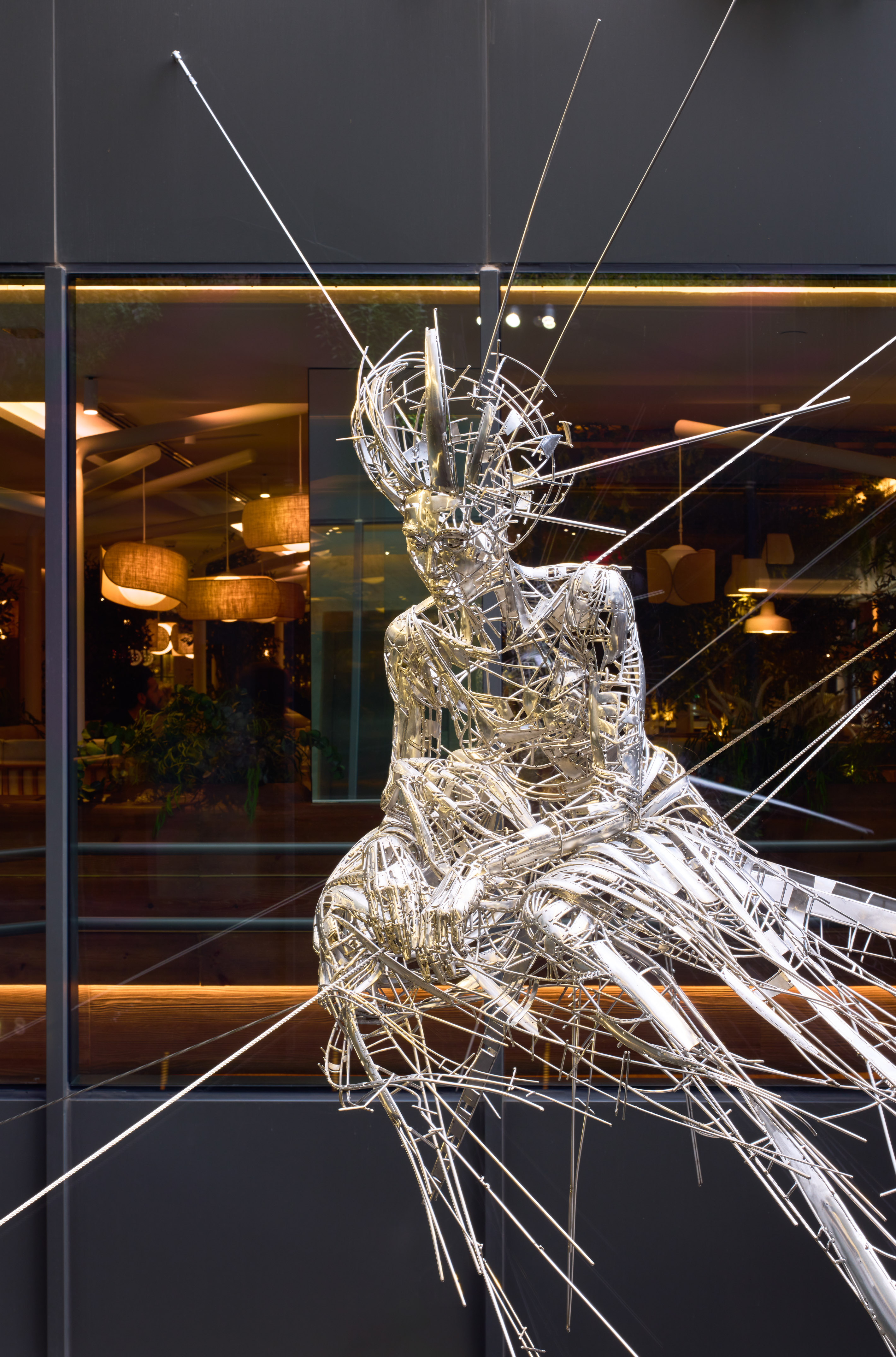 Abstract metal wire sculpture of figure with spiked head, window display.