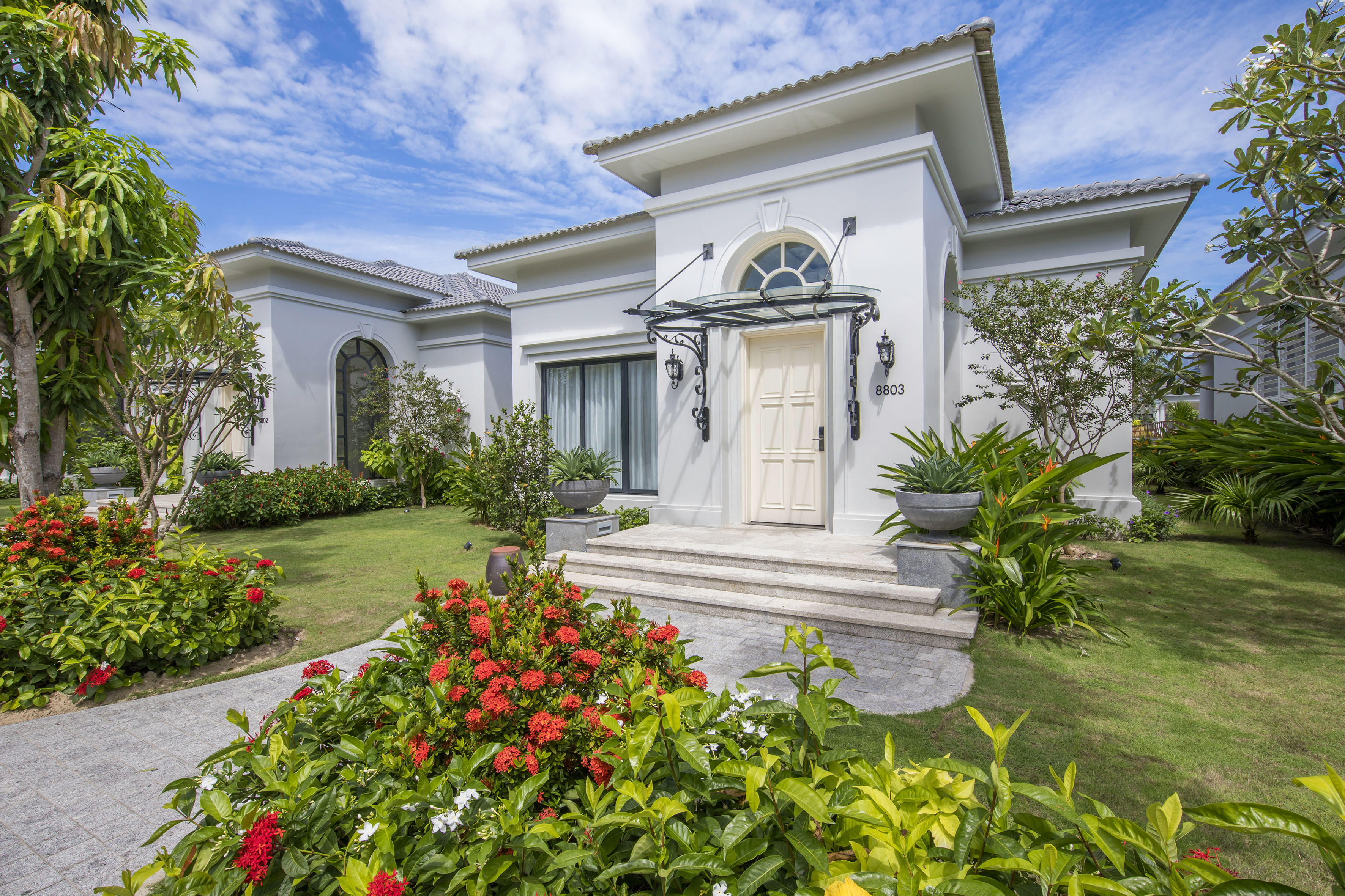 Modern white villa with landscaped tropical garden and stone pathway.
