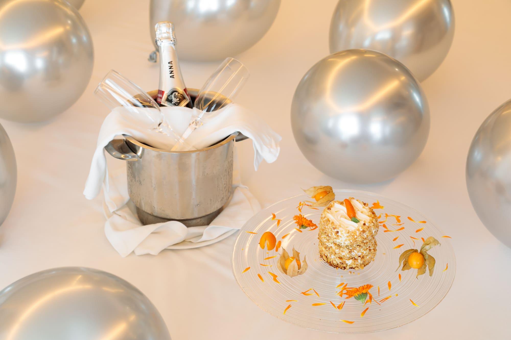 a champagne in a bucket with glasses and a cake on a table