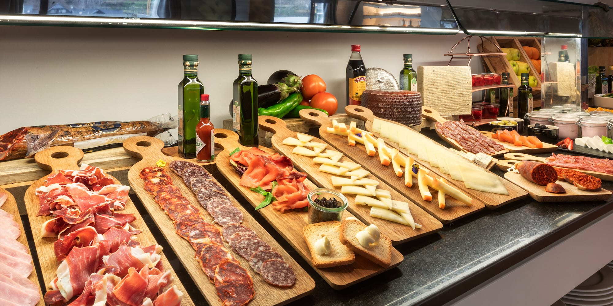 a counter with different types of meat on wooden boards
