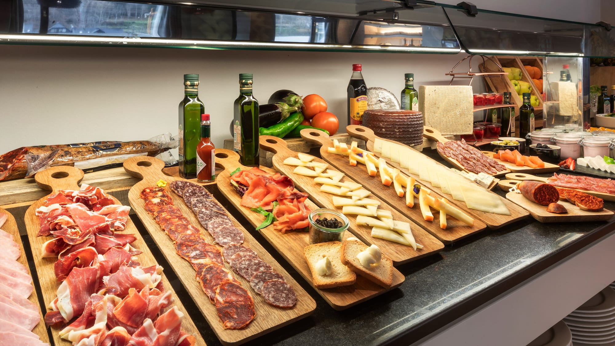 a counter with different types of meat on wooden boards