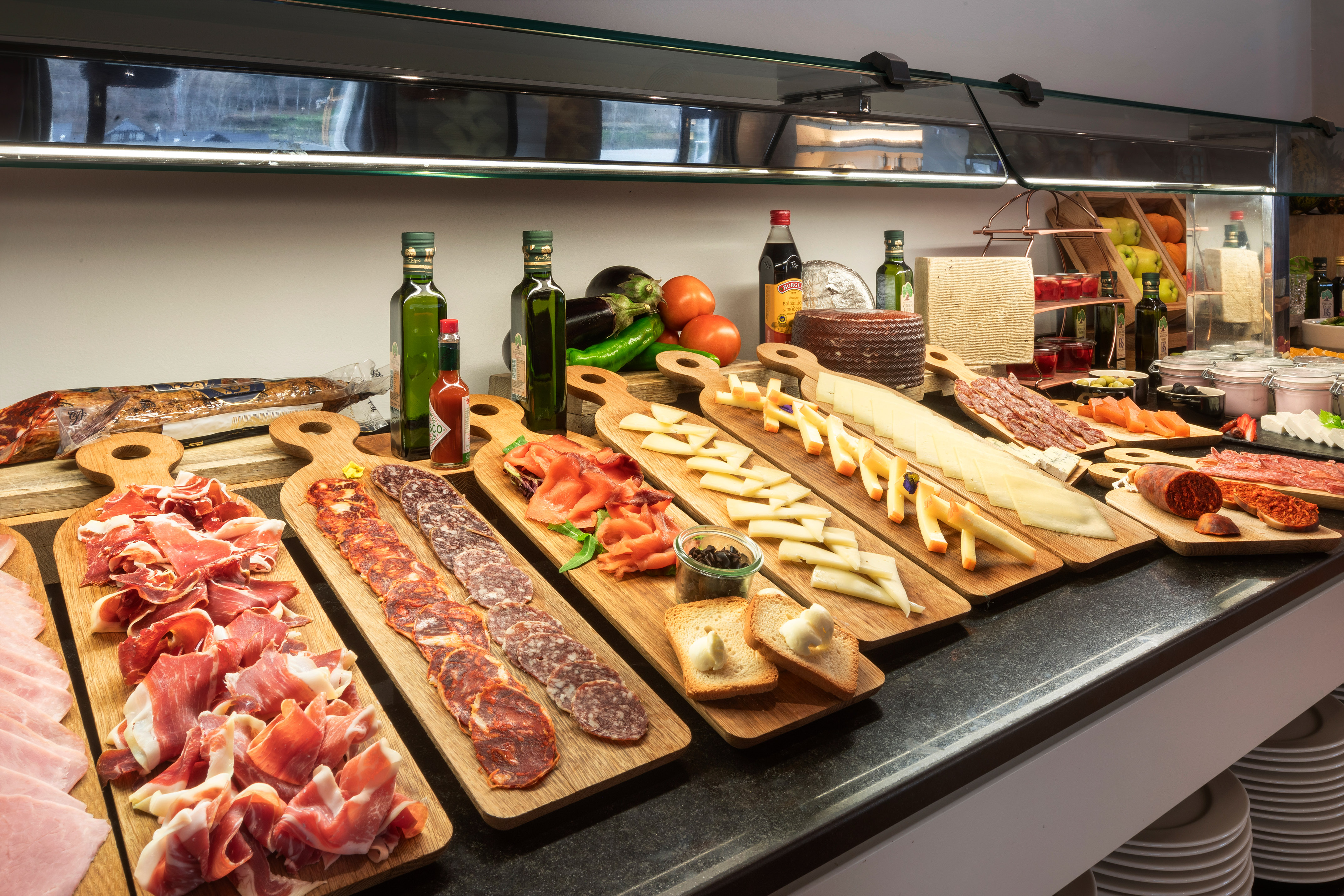 Charcuterie and cheese buffet with cured meats, smoked salmon, and olive oil.