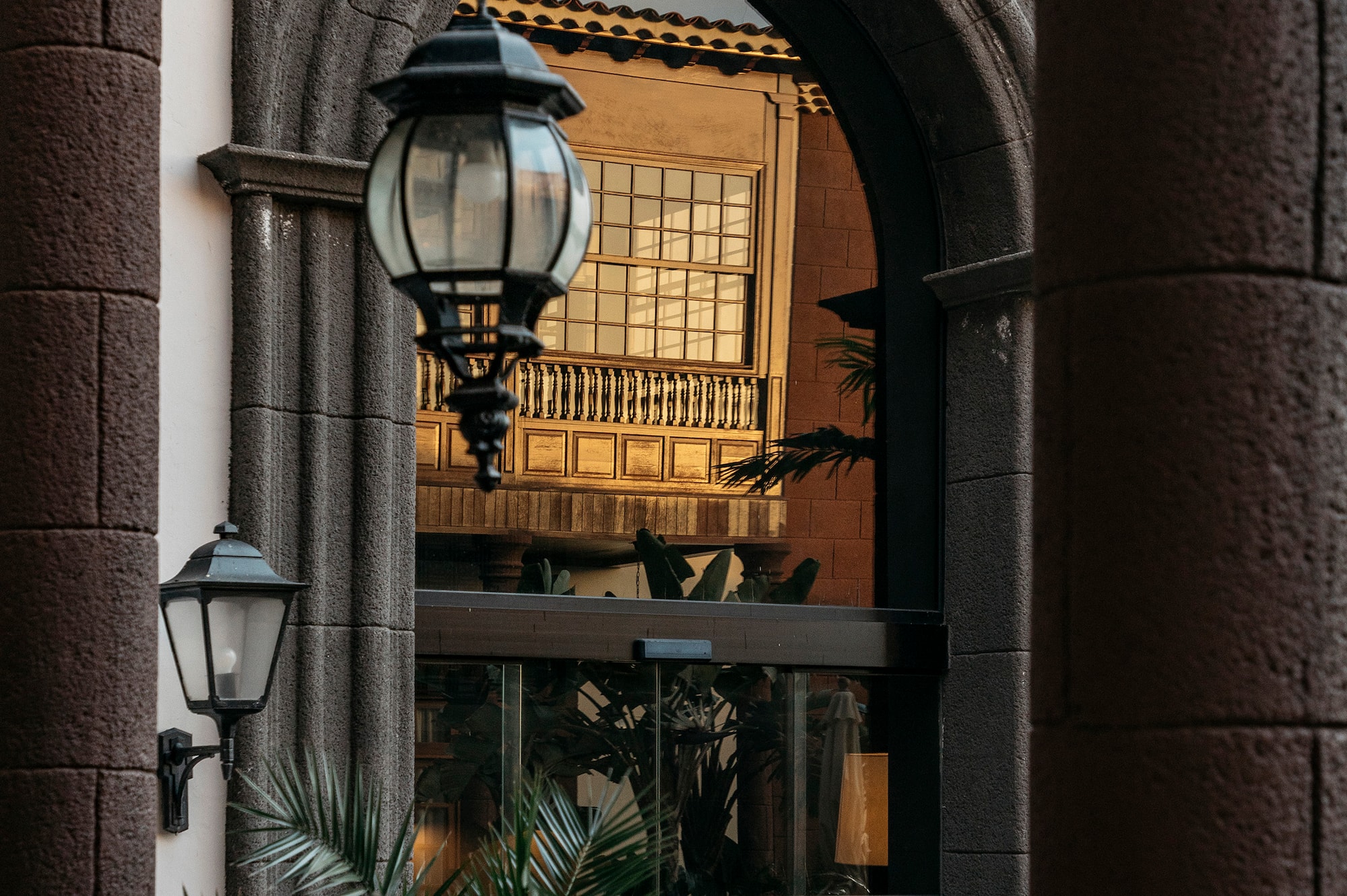 Ornate stone archway, hanging lantern, traditional building with golden light.