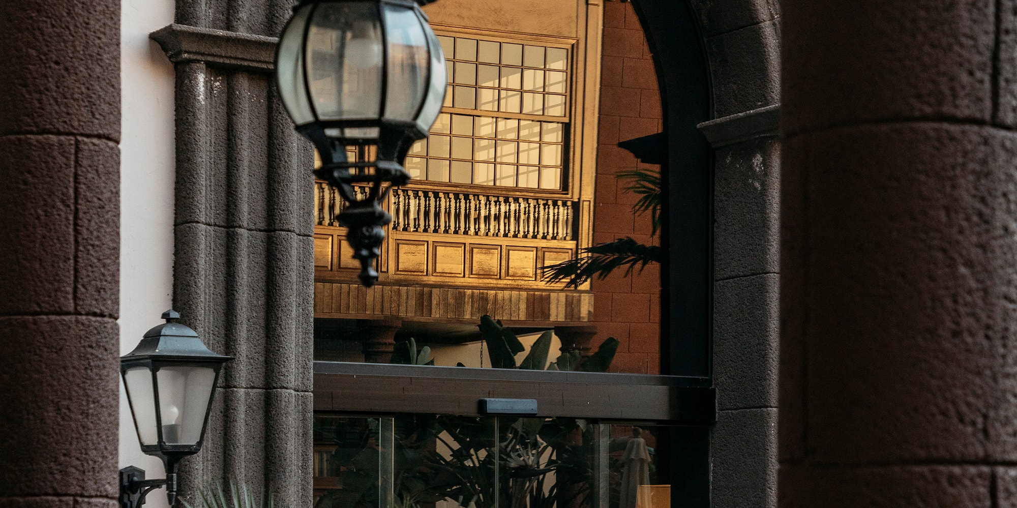Ornate stone archway, hanging lantern, traditional building with golden light.