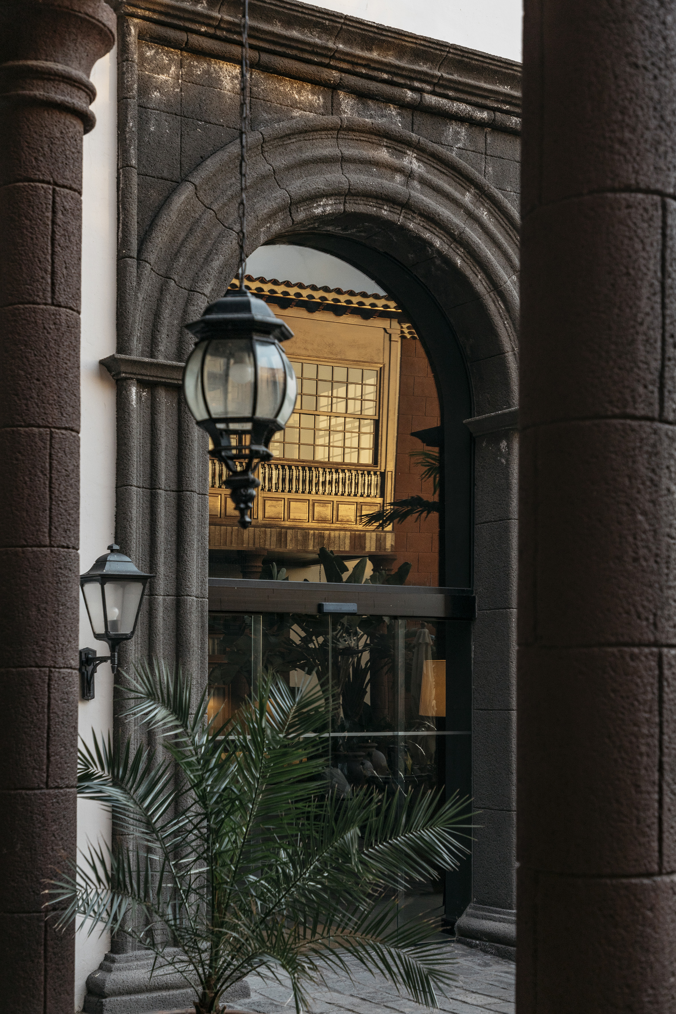 Ornate stone archway, hanging lantern, traditional building with golden light.