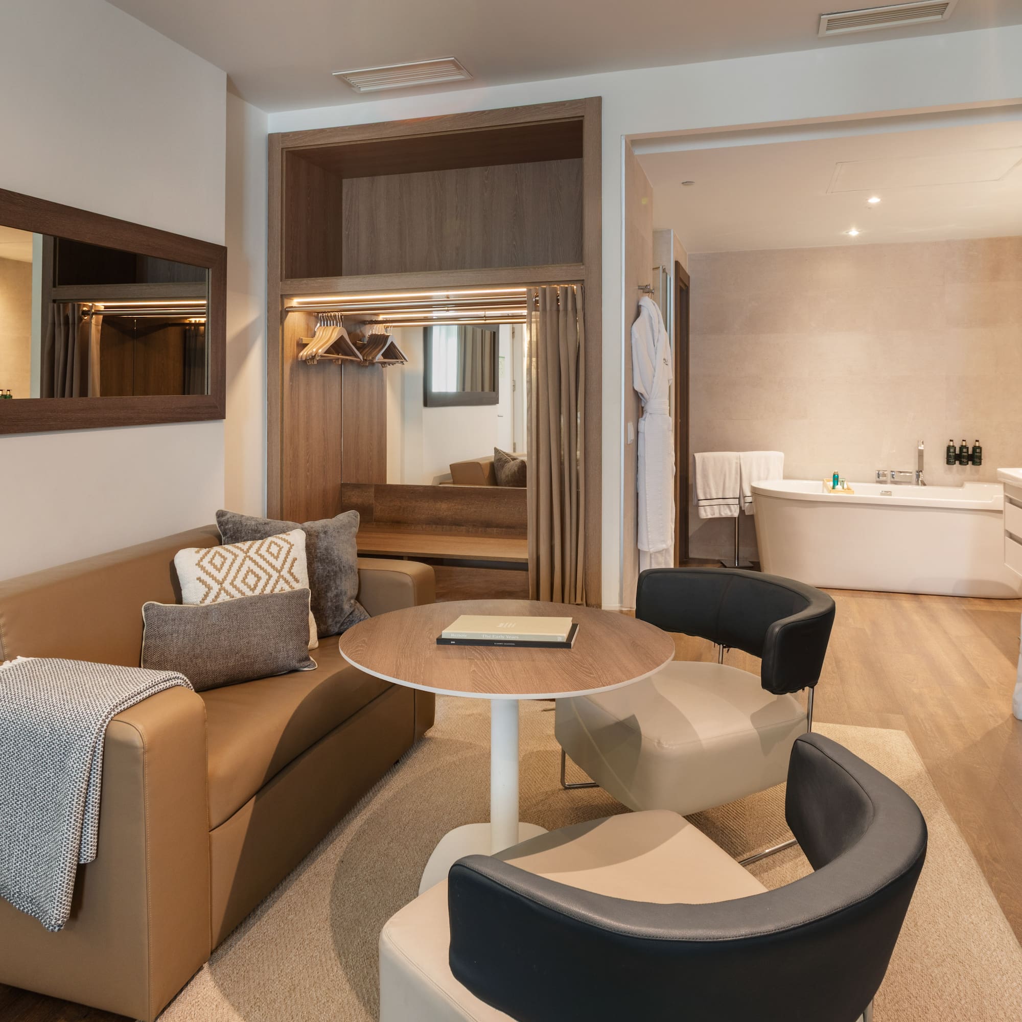 Hotel suite living area with sofa, coffee table, and view to modern bathtub.