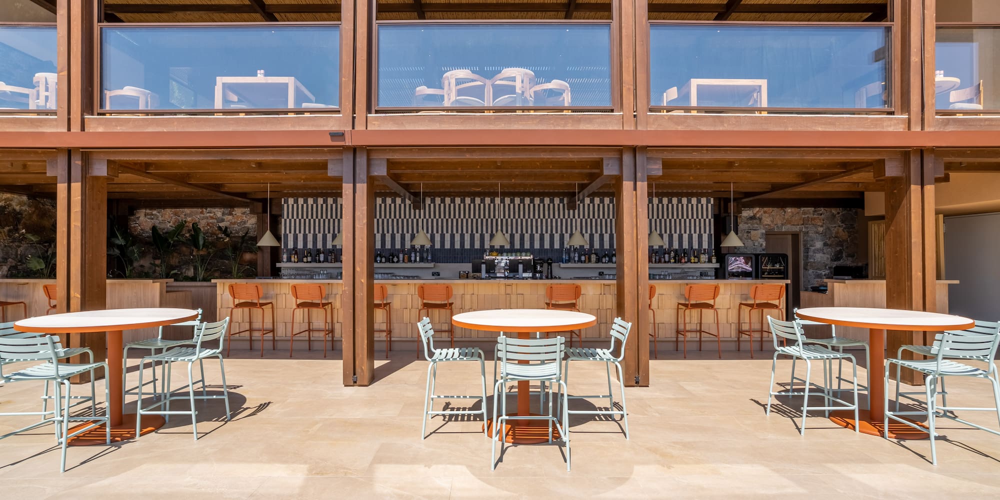 Outdoor resort bar with light blue chairs, orange bar stools, and bamboo ceiling.