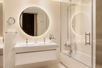 a bathroom with a round mirror and a tub