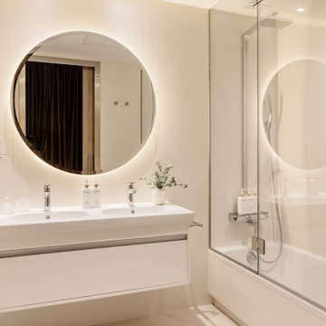 a bathroom with a round mirror and a tub