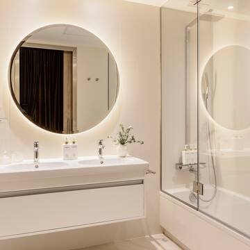a bathroom with a round mirror and a tub