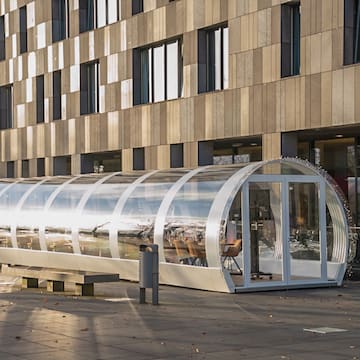 a glass covered shelter in front of a building