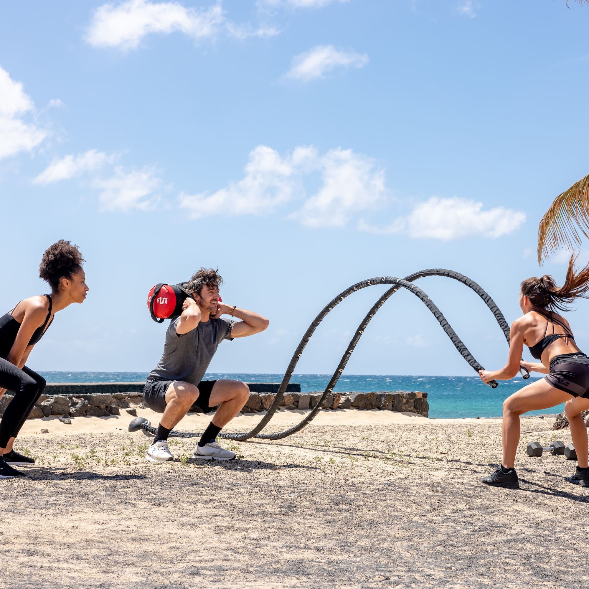 a group of people playing with a rope on a beach